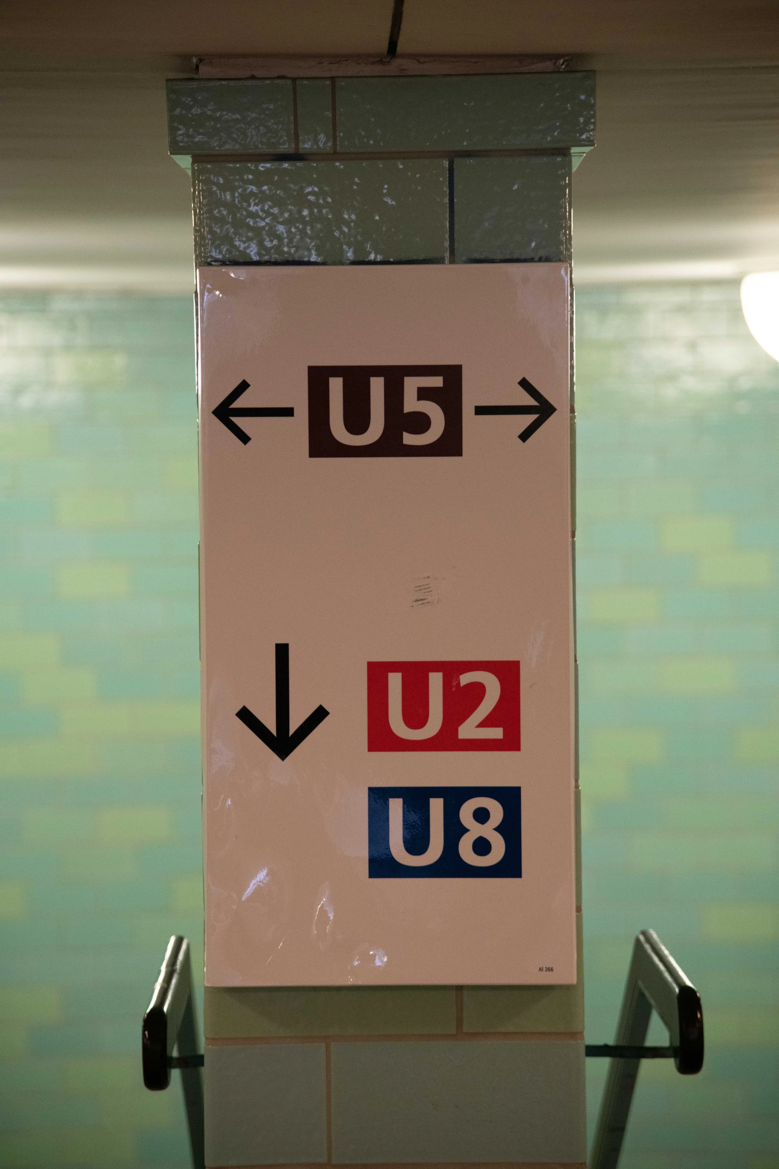 Sign on a pillar in a subway station showing directions for U5, U2, and U8 subway lines with arrows indicating directions.