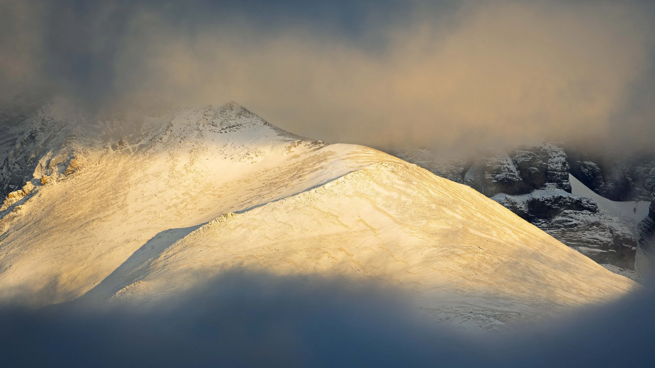 Snow-covered mountain peak with clouds and sunlight
