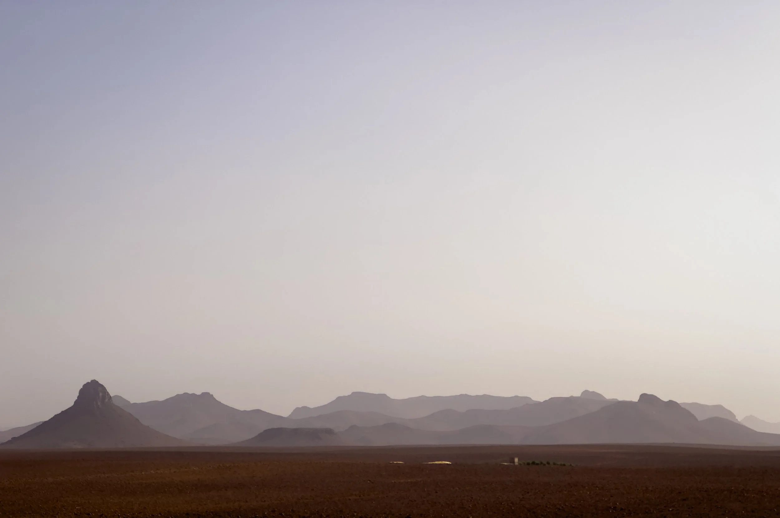 Desert landscape with distant mountains and a clear sky.