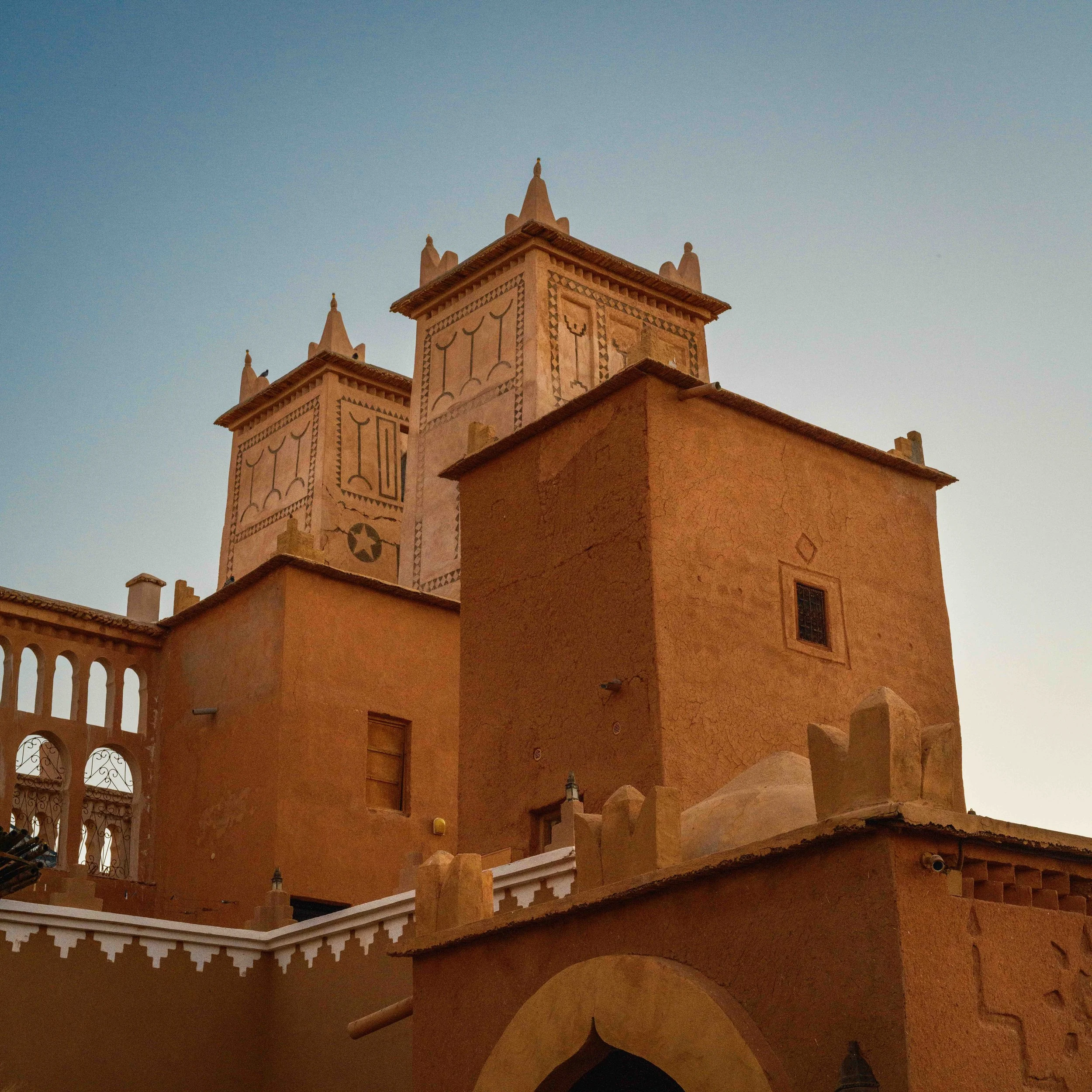 Traditional Moroccan building with adobe walls and decorative towers under a clear sky