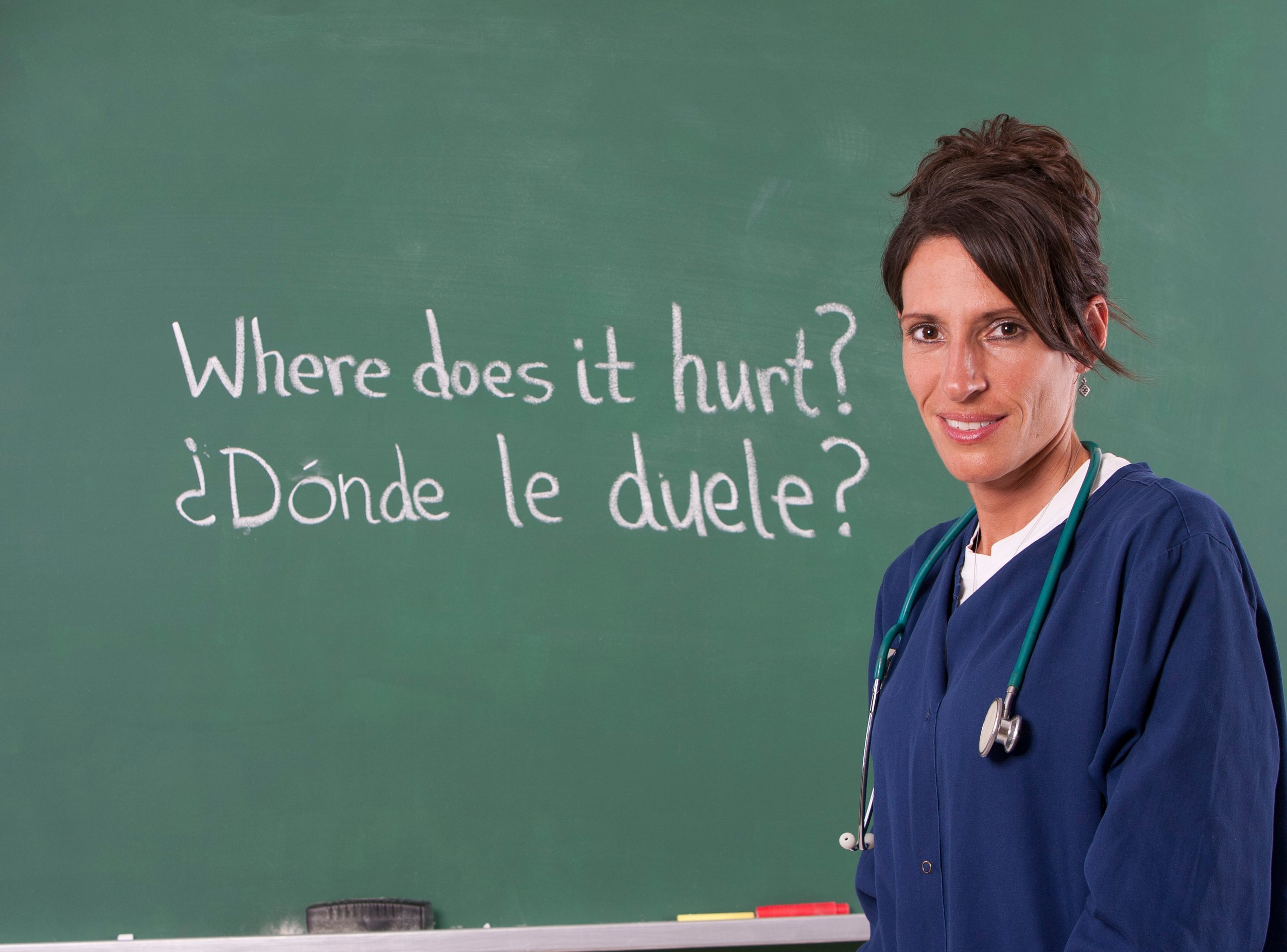 Healthcare worker in a classroom with Spanish written on the chalkboard