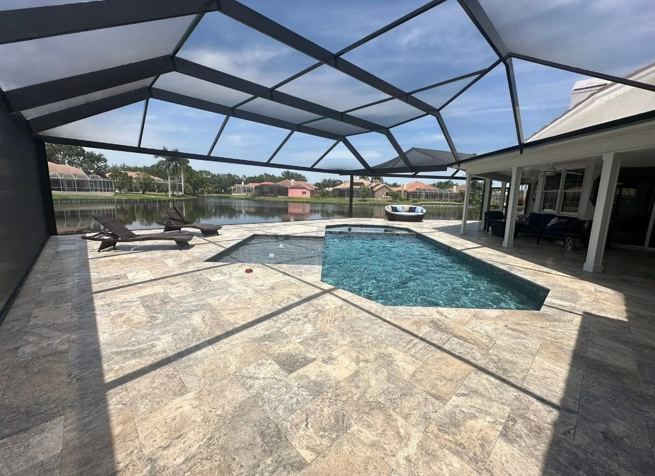 screened-in backyard patio with a small swimming pool, two lounge chairs, and a view of a pond with houses in the background.