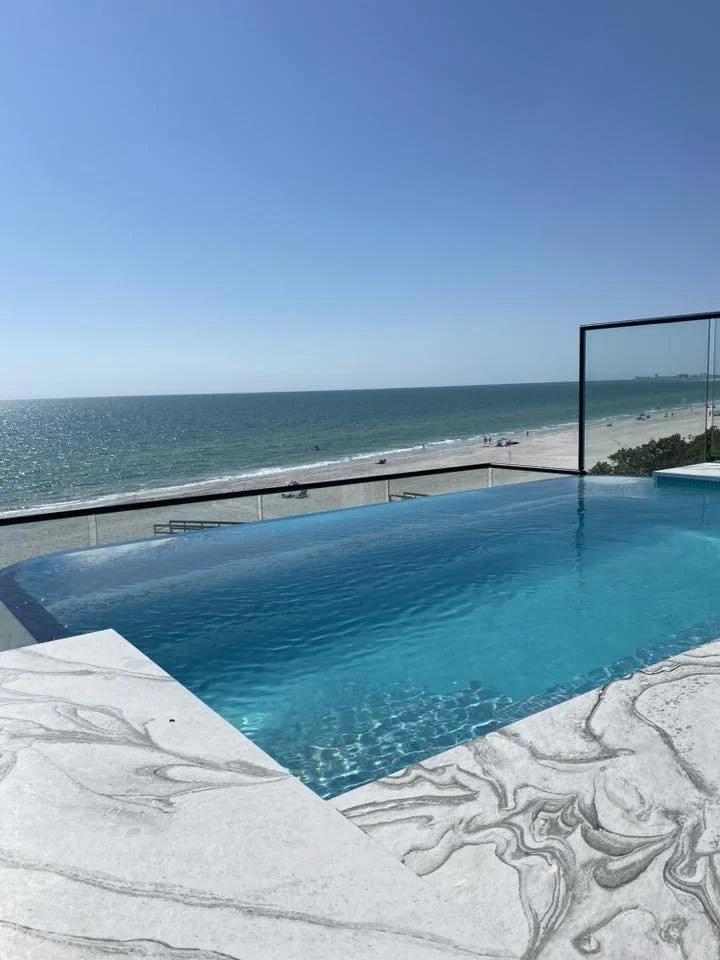 An infinity pool with a view of the ocean and a clear blue sky.