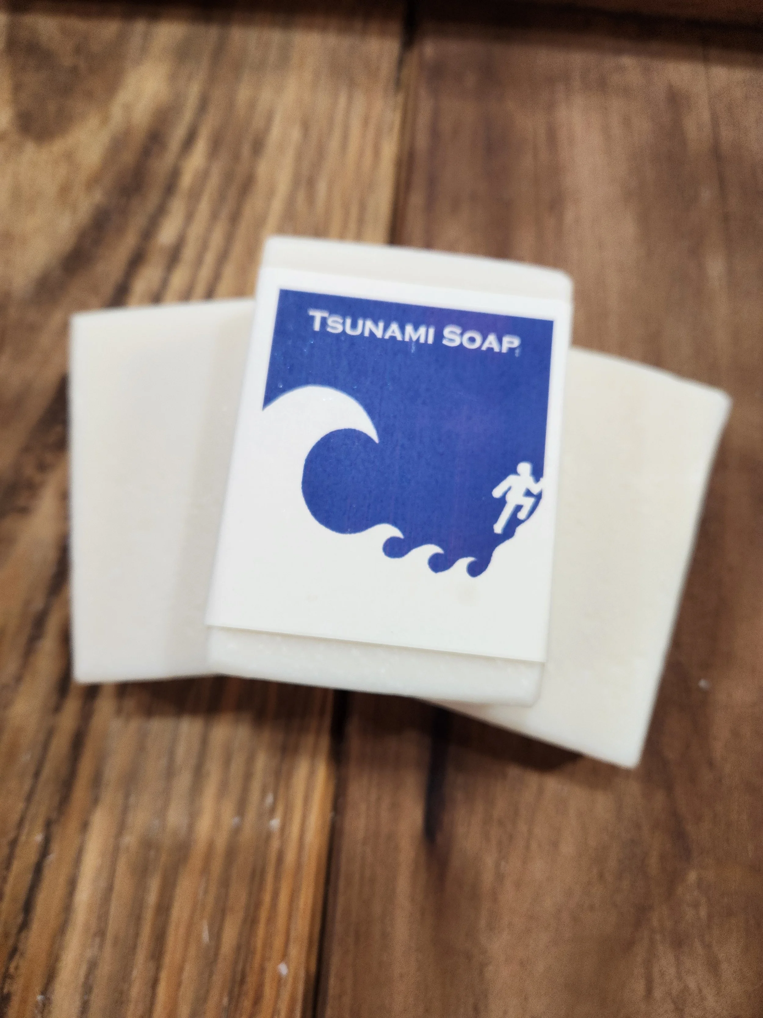 3 bars of white soap on a wooden base, the Tsunami pictogram is noted on the front label.