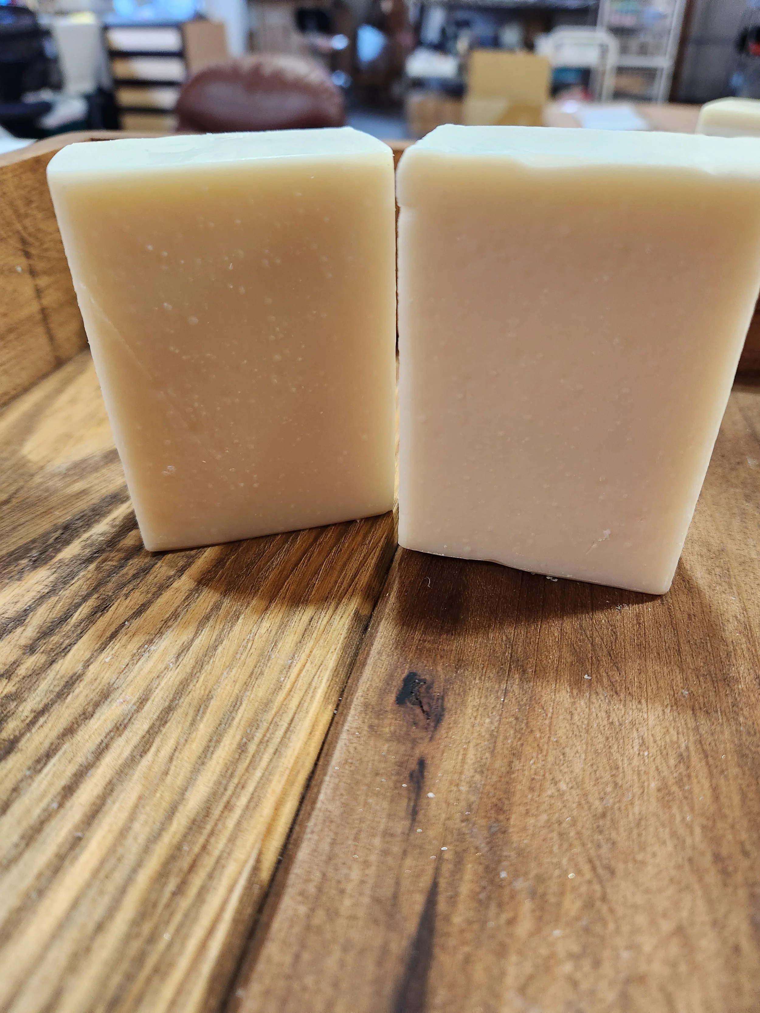 2 bars of white soap on a wooden background.