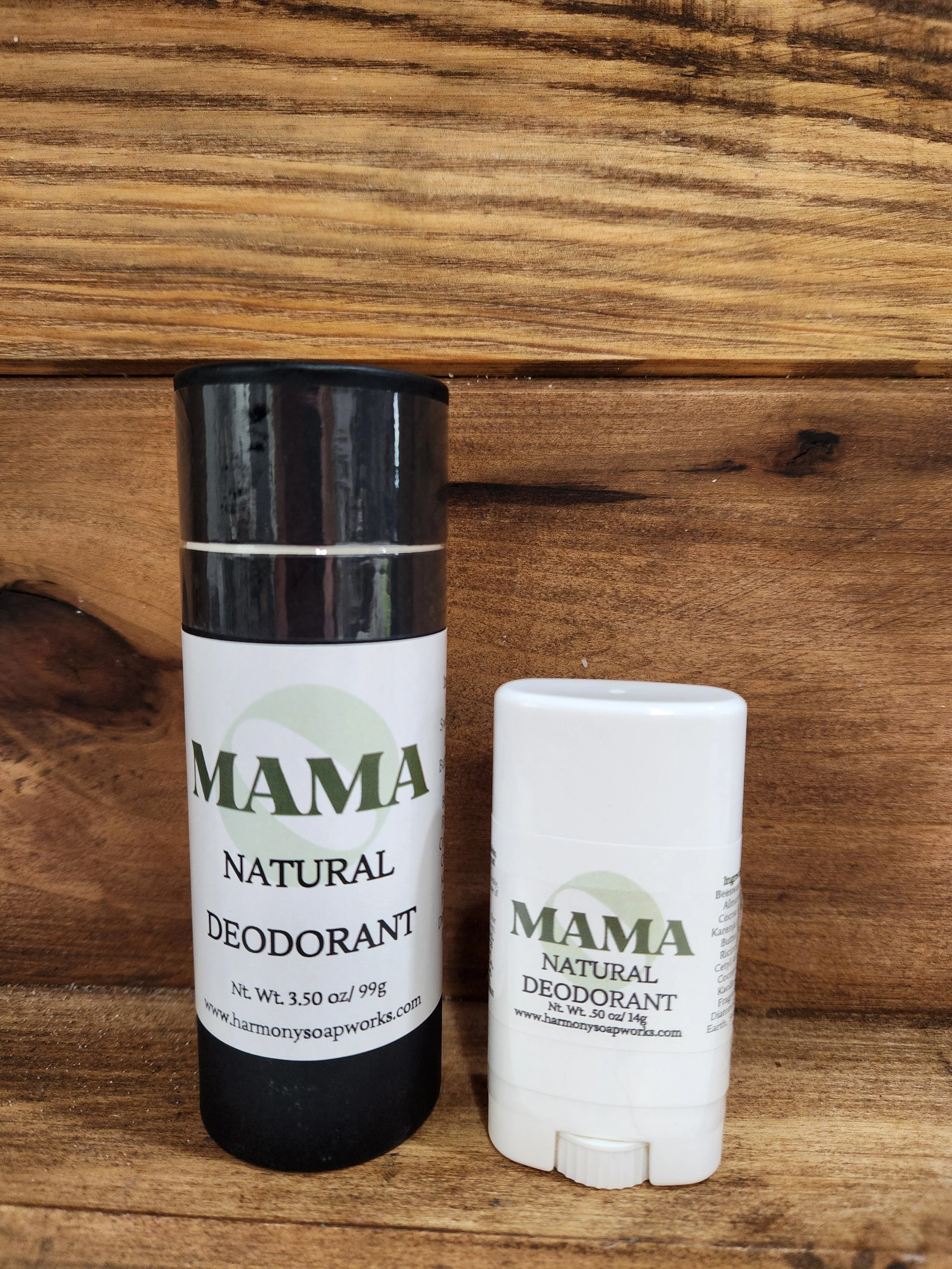 image of a black paper deodorant tube sized 3.5oz and a small white plastic trial sized .50oz deodorant tube with a wood grain background.