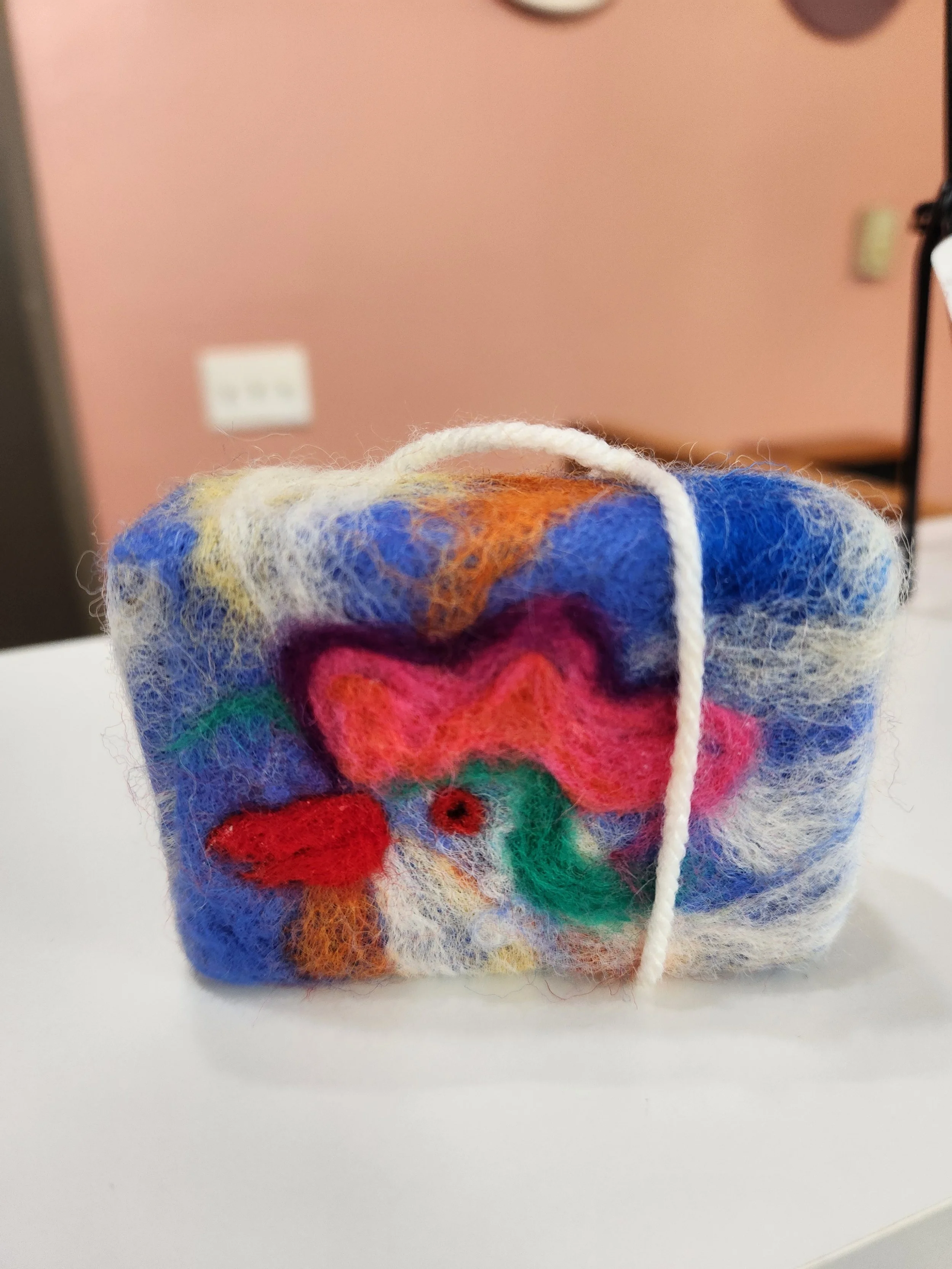 one bar of soap with an image of a chicken head needle felted over the wool wrapped soap.