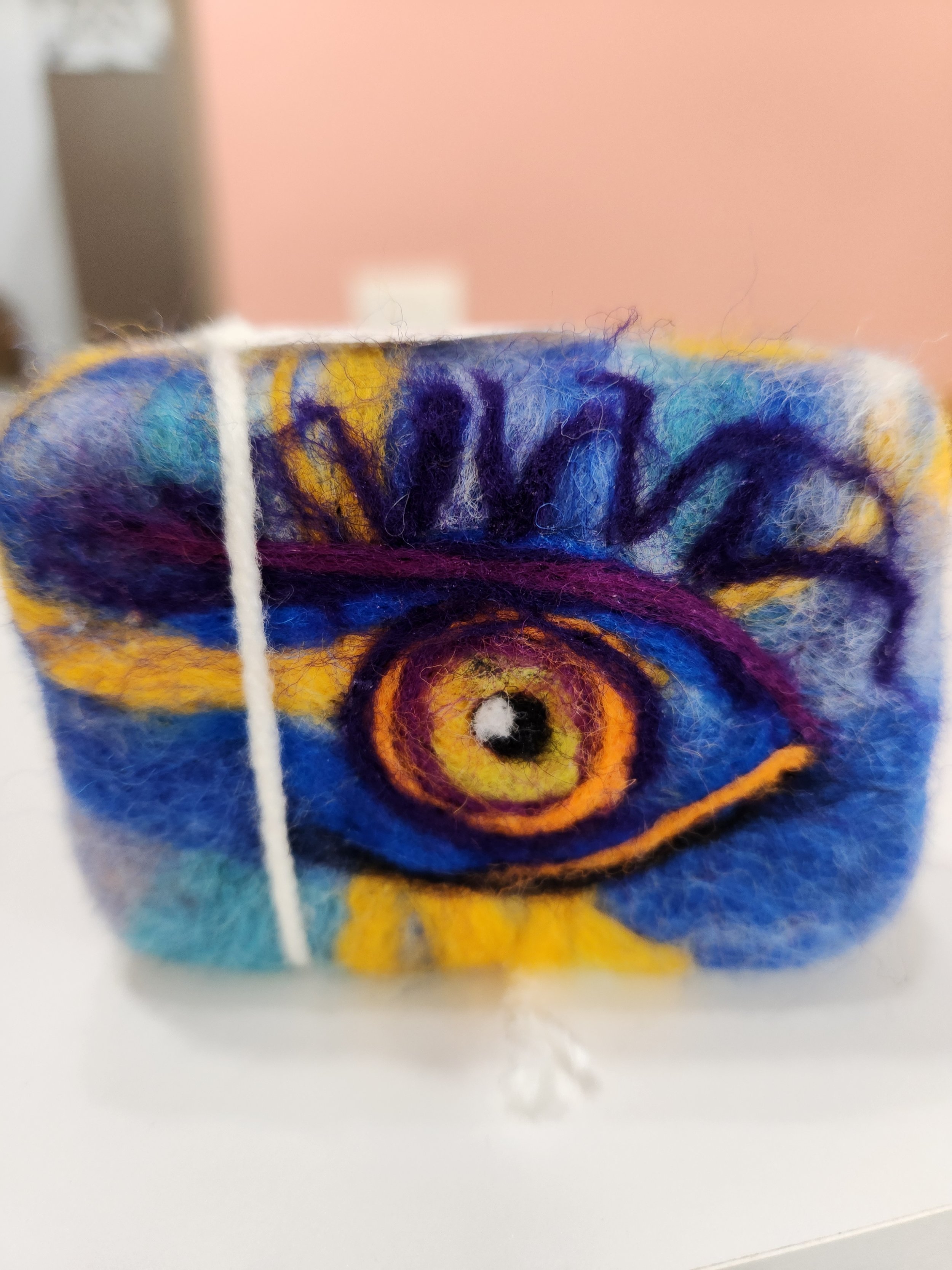 one bar of wool wrapped soap, with the image of an artistic eye needle felted onto the base wool.