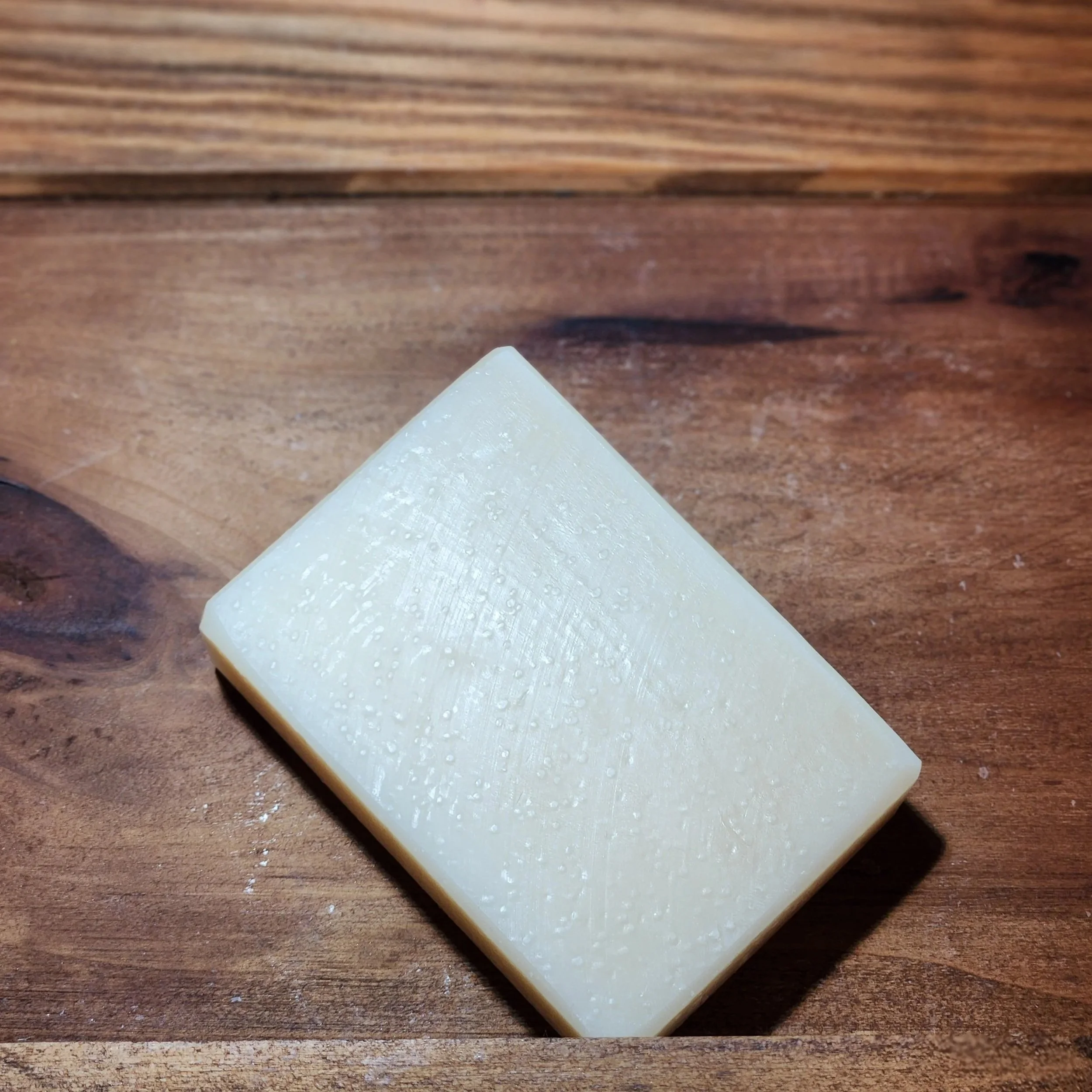 White bar of soap with a brown wood grain background.