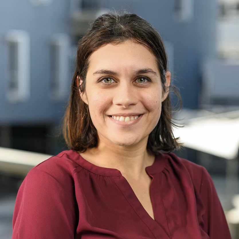 An indigenous woman, smiling at the camera in a close up portrait, posing for a indigenous scholarship program as a mentor