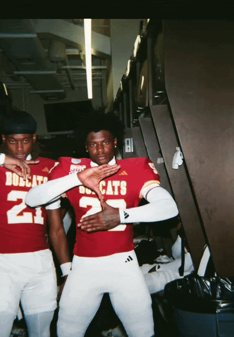 Two football players in red jerseys with 'Bulldogs' and numbers 24 and 22, making celebratory poses indoors.
