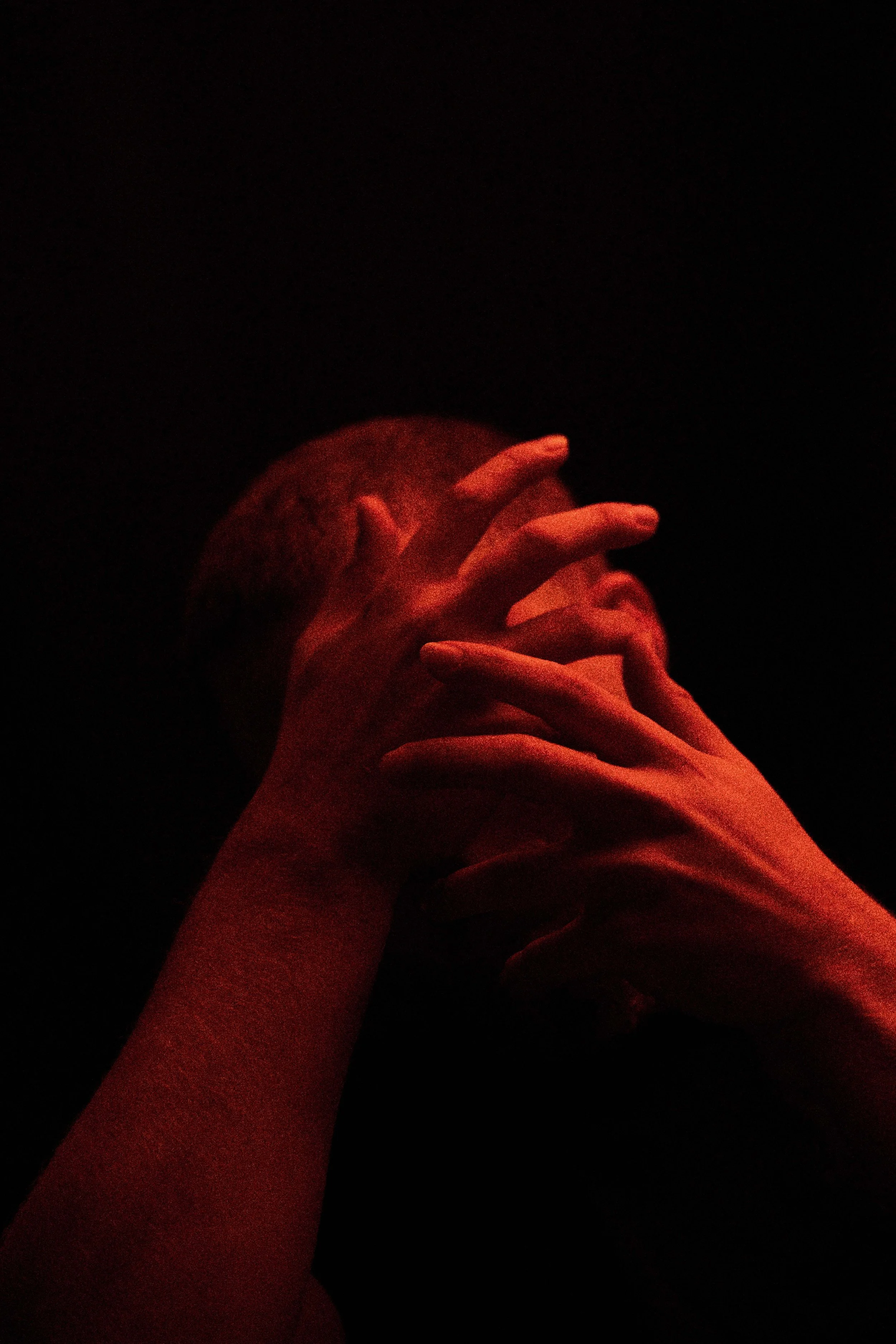 Close-up of hands holding a red object against a dark background with red lighting.