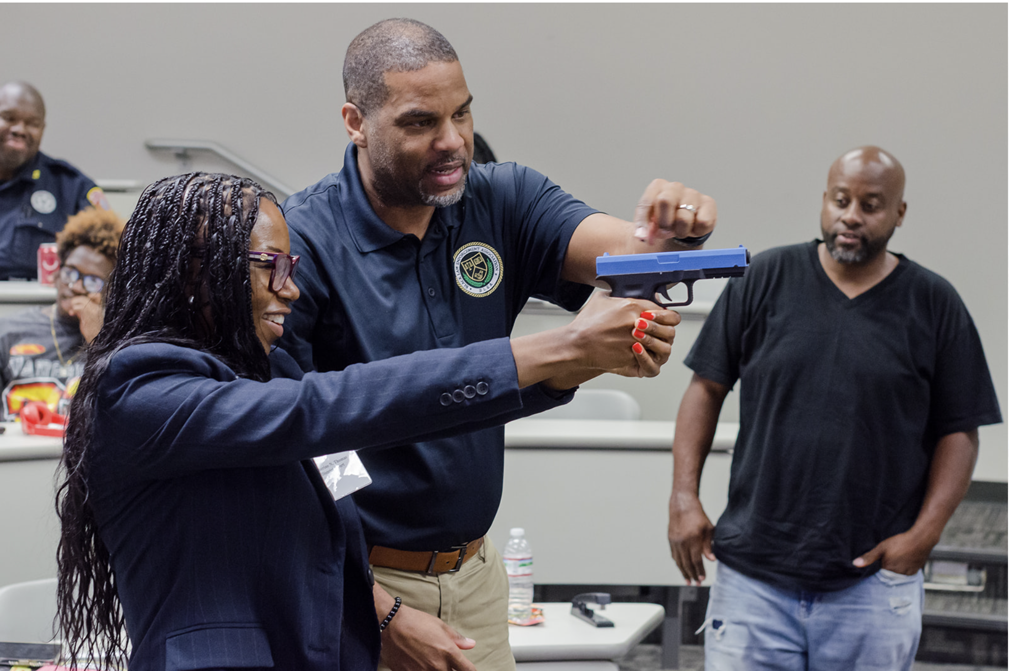 Black instructor demonstrating safe firearm handling to a Black participant