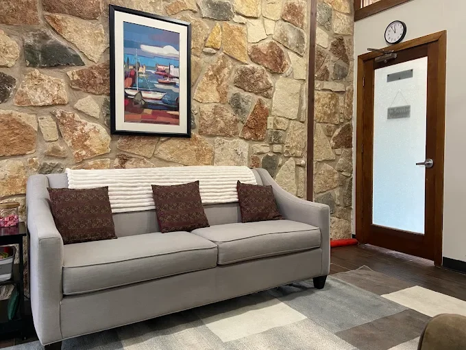 Image of the North Austin office with a grey couch in front of rock wall with colorful artwork above.