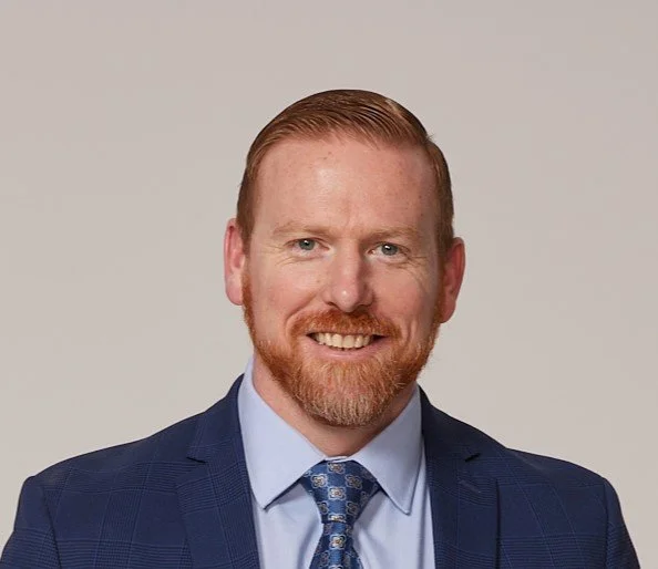 Headshot photo of Alex Penrod, MS, LPC, LCDC, Founder of Neuro Nuance Therapy and EMDR, PLLC wearing blue blazer jacket, light blue shirt, and blue tie.