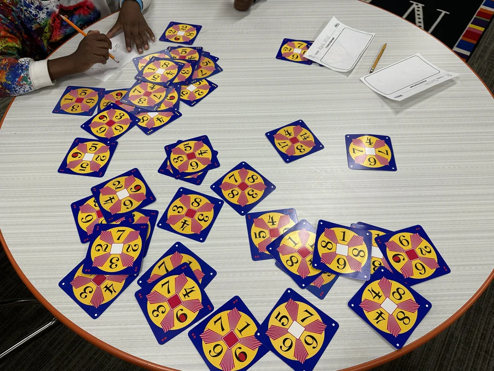 Math 24 cards spread across a table during a community game day