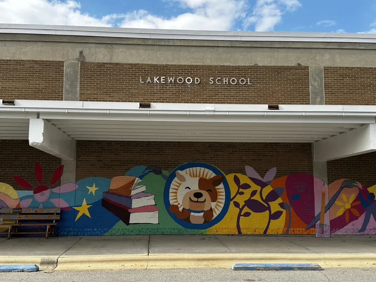 Colorful student mural of books, stars and a smiling lion at Lakewood School