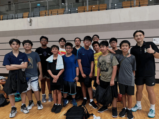 Group of young boys and a female adult standing on a gymnasium floor, posing for a photo.