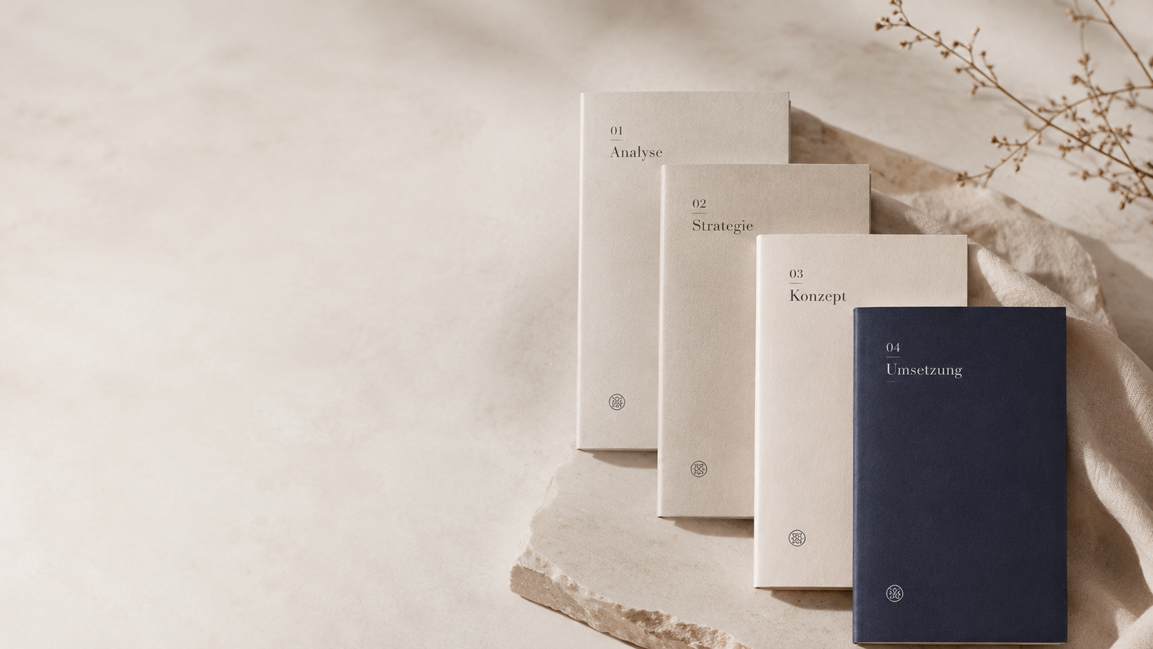 Vier gebundene Bücher in neutralen Farben mit deutschen Titeln, die auf einer Steinformation liegen, mit Wasserpflanzen im Hintergrund.