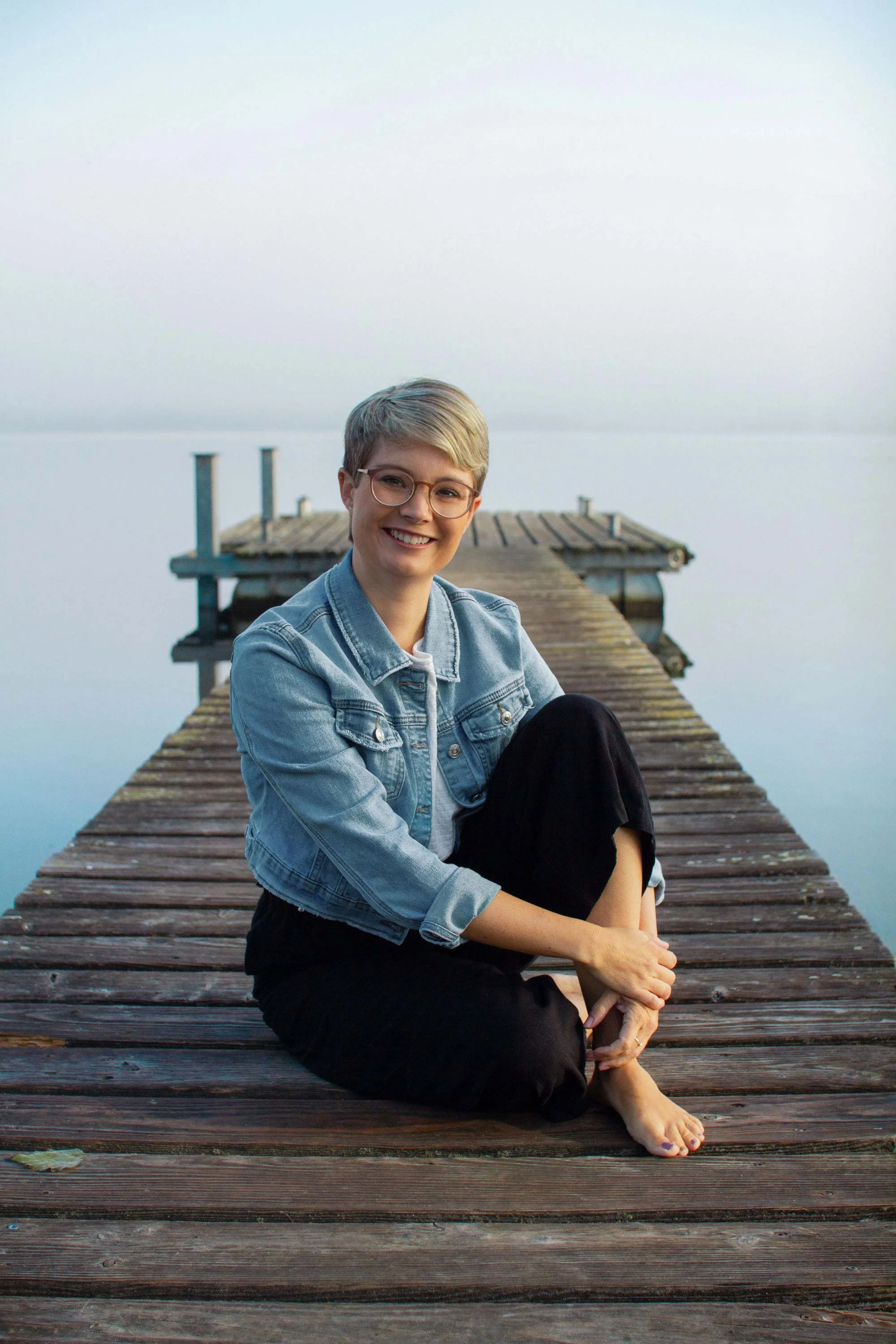Human Design Coach Eva Weiss auf einem Steg sitzend am See