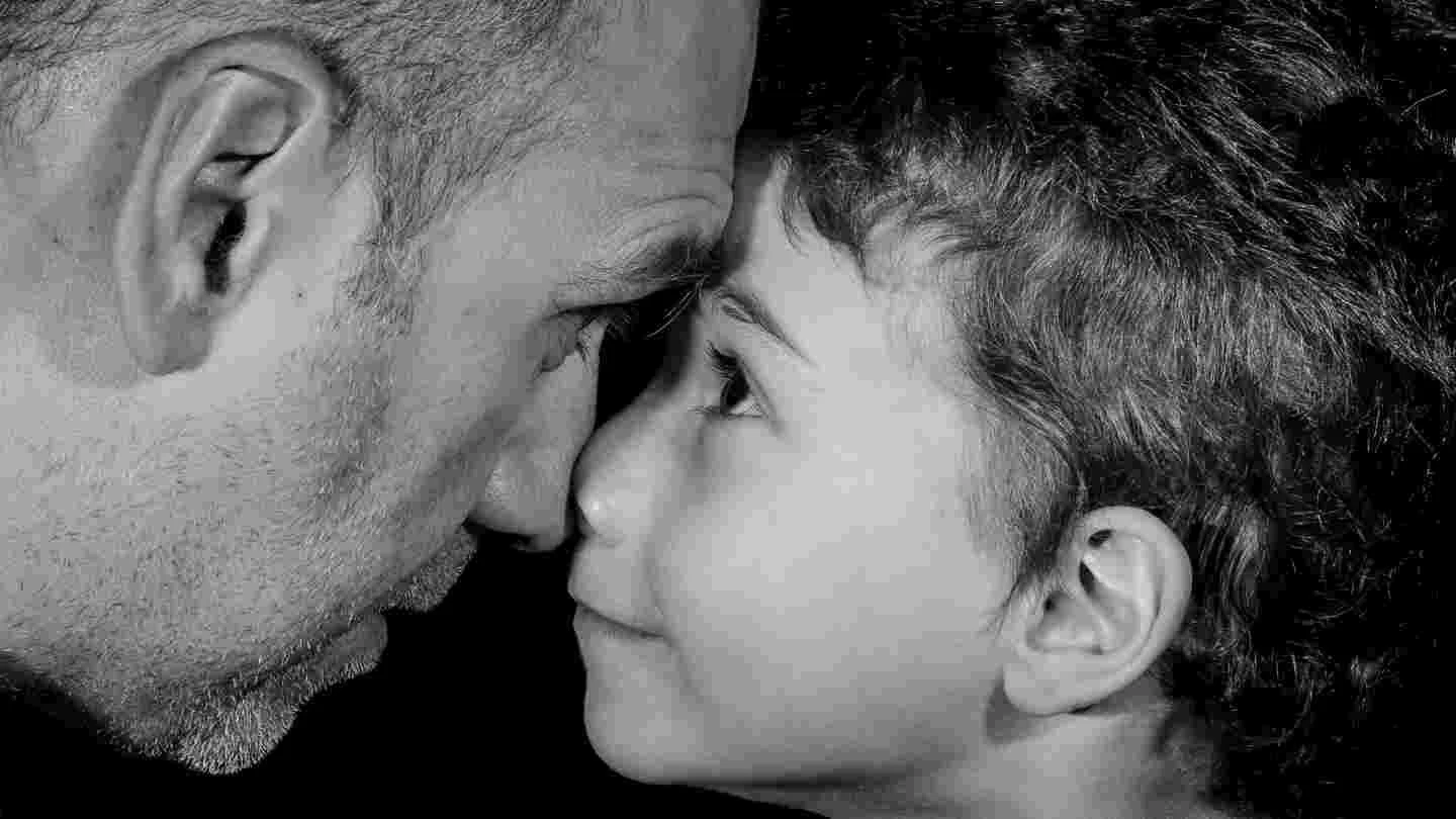 Vater und Sohn haben Stirn und Nase aneinandergelehnt und schauen sich tief in die Augen