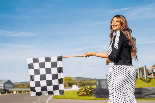 Woman stood smiling holding a black and white checked flag 