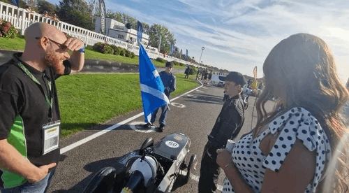  Man and woman looking at a kit car on a race track 
