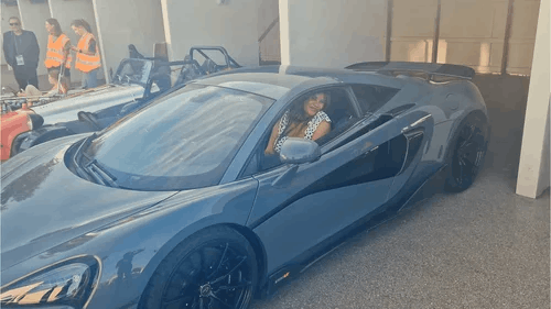 A woman smiling sat in a sports car 