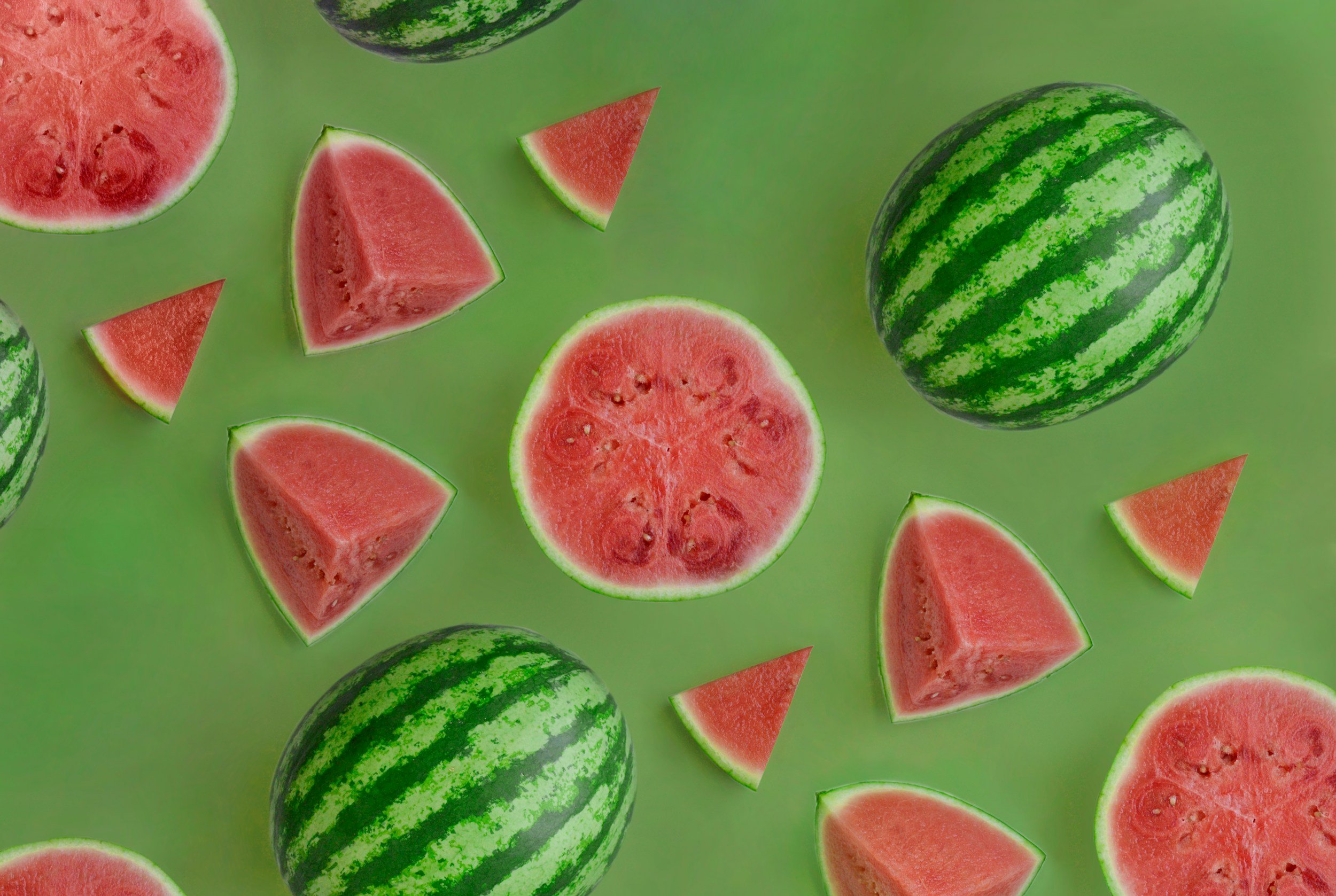Whole and sliced watermelons on a green background.