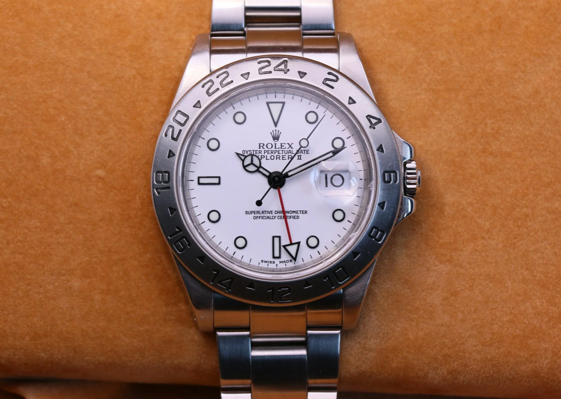 A close-up of a Rolex Explorer II watch with a white polar dial and a steel oyster bracelet.