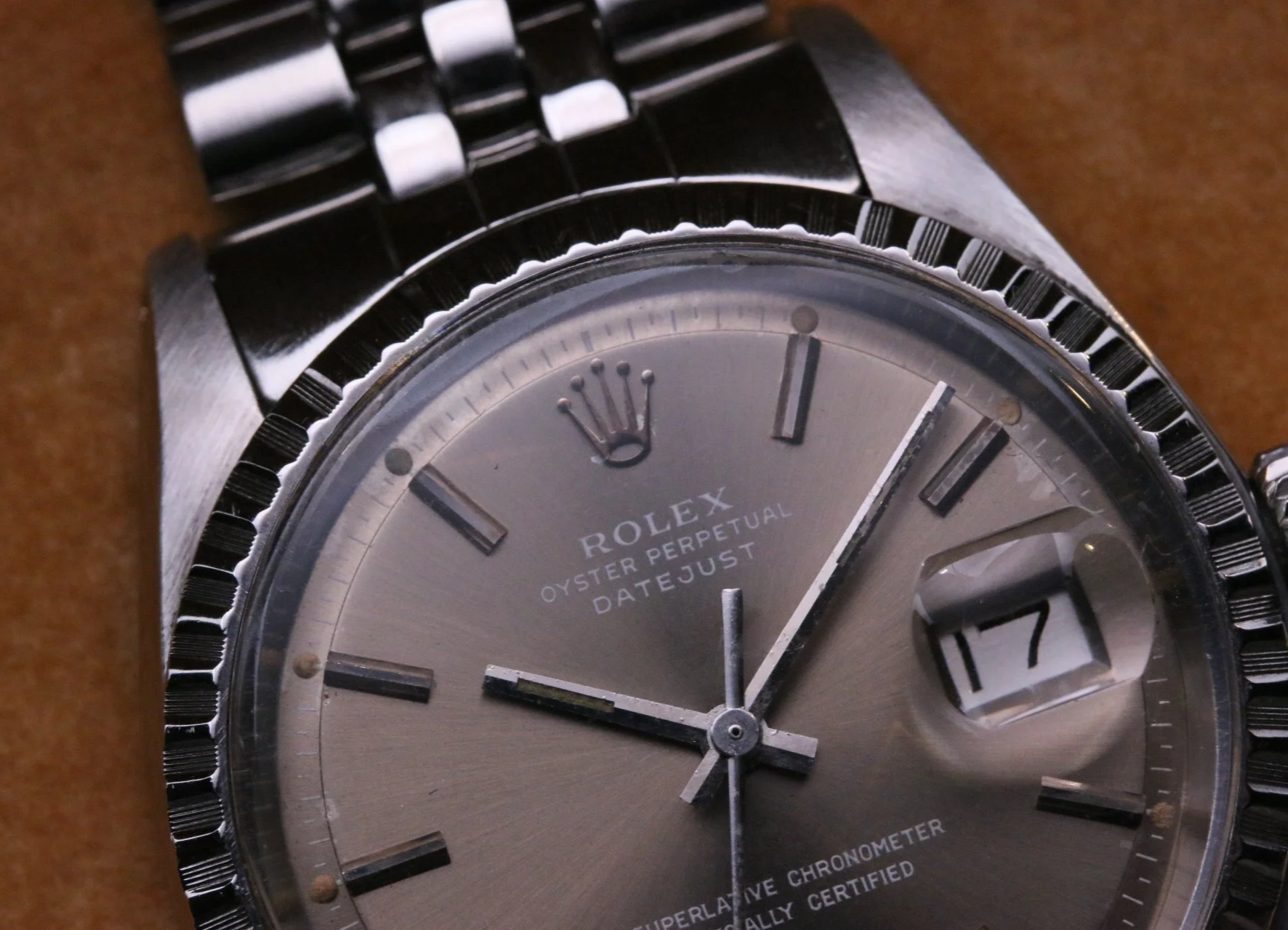 A close-up of a Rolex Datejust watch showing a grey sigma dial and jubilee bracelet