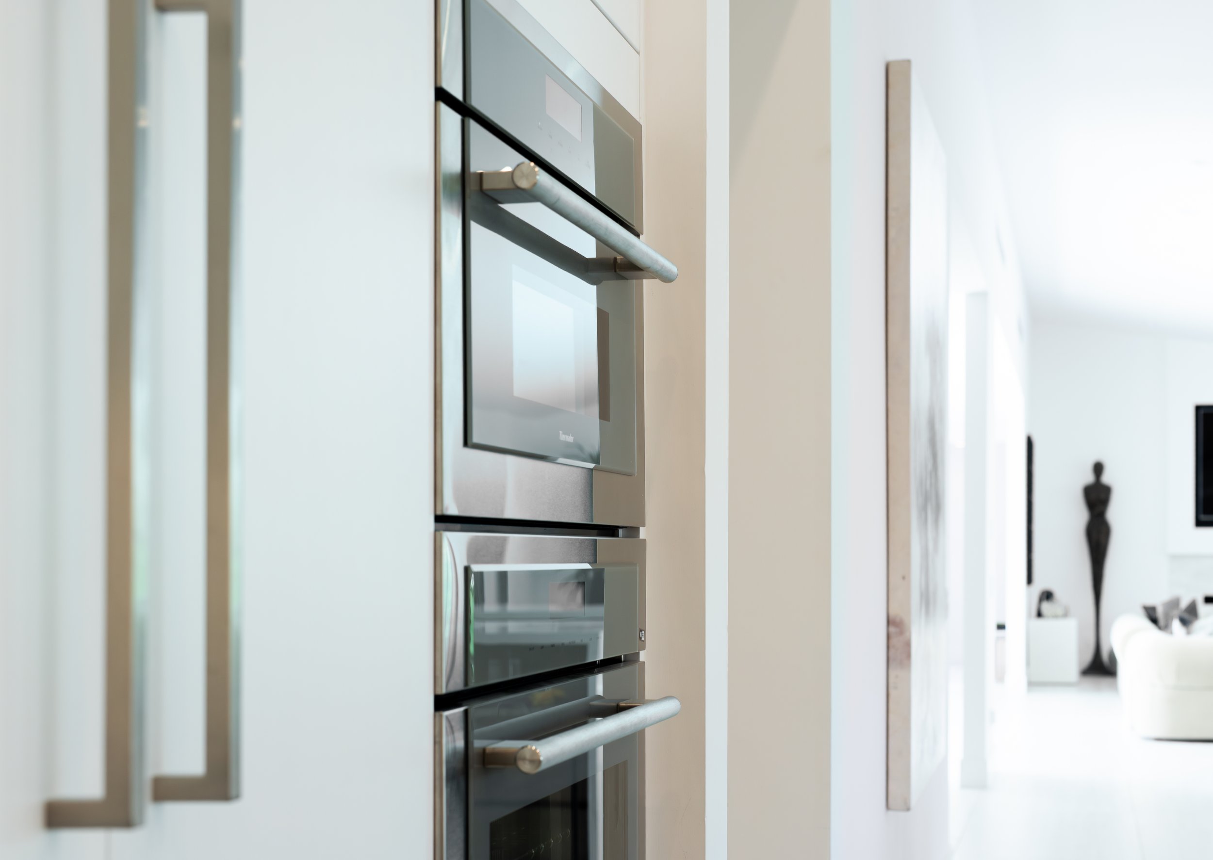 Close-up of modern high-end kitchen appliances, including an oven, built into a sleek white kitchen cabinet in a luxury property in La Quinta CA. 