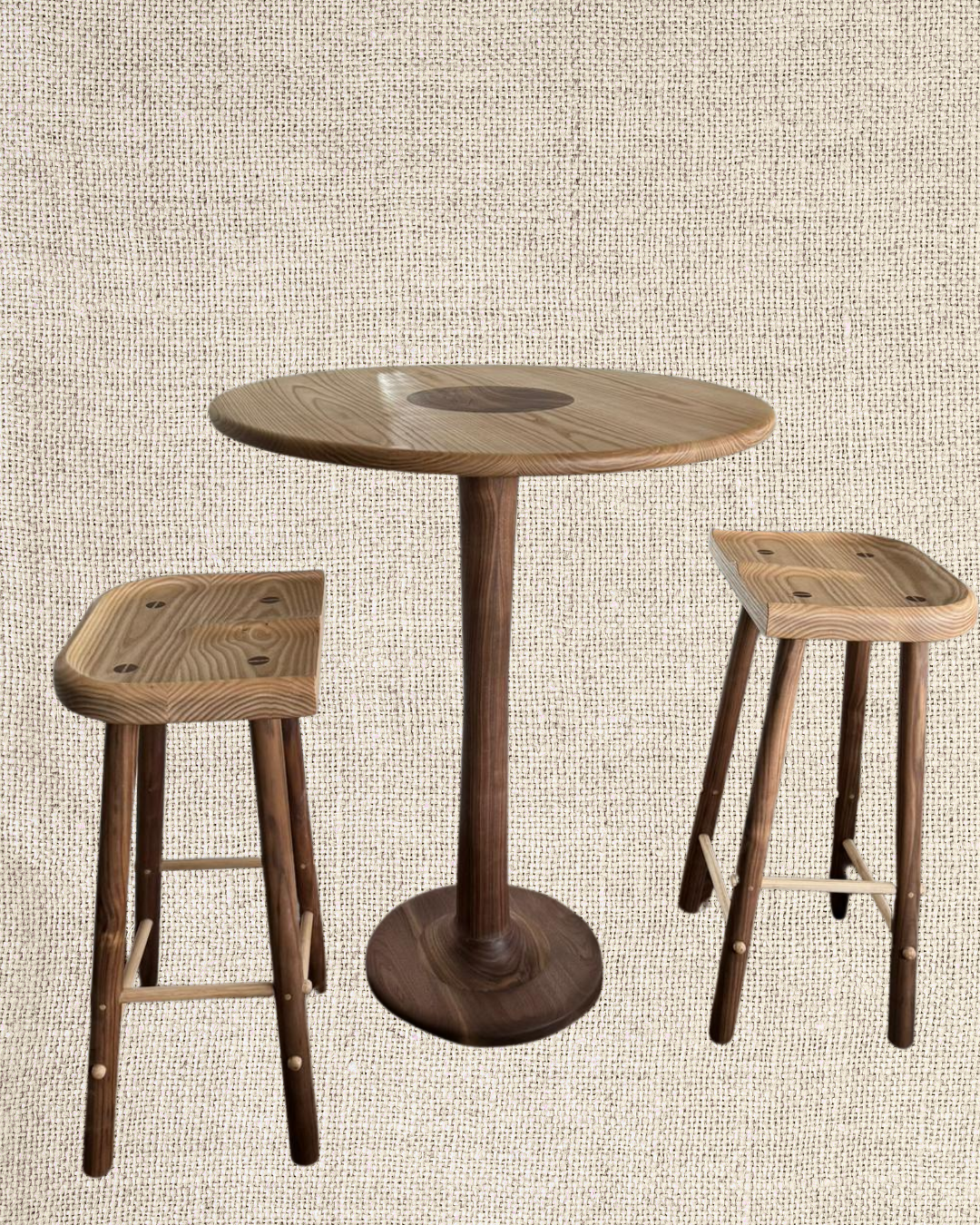 Wooden bar table with two matching wooden stools against a beige textured background.
