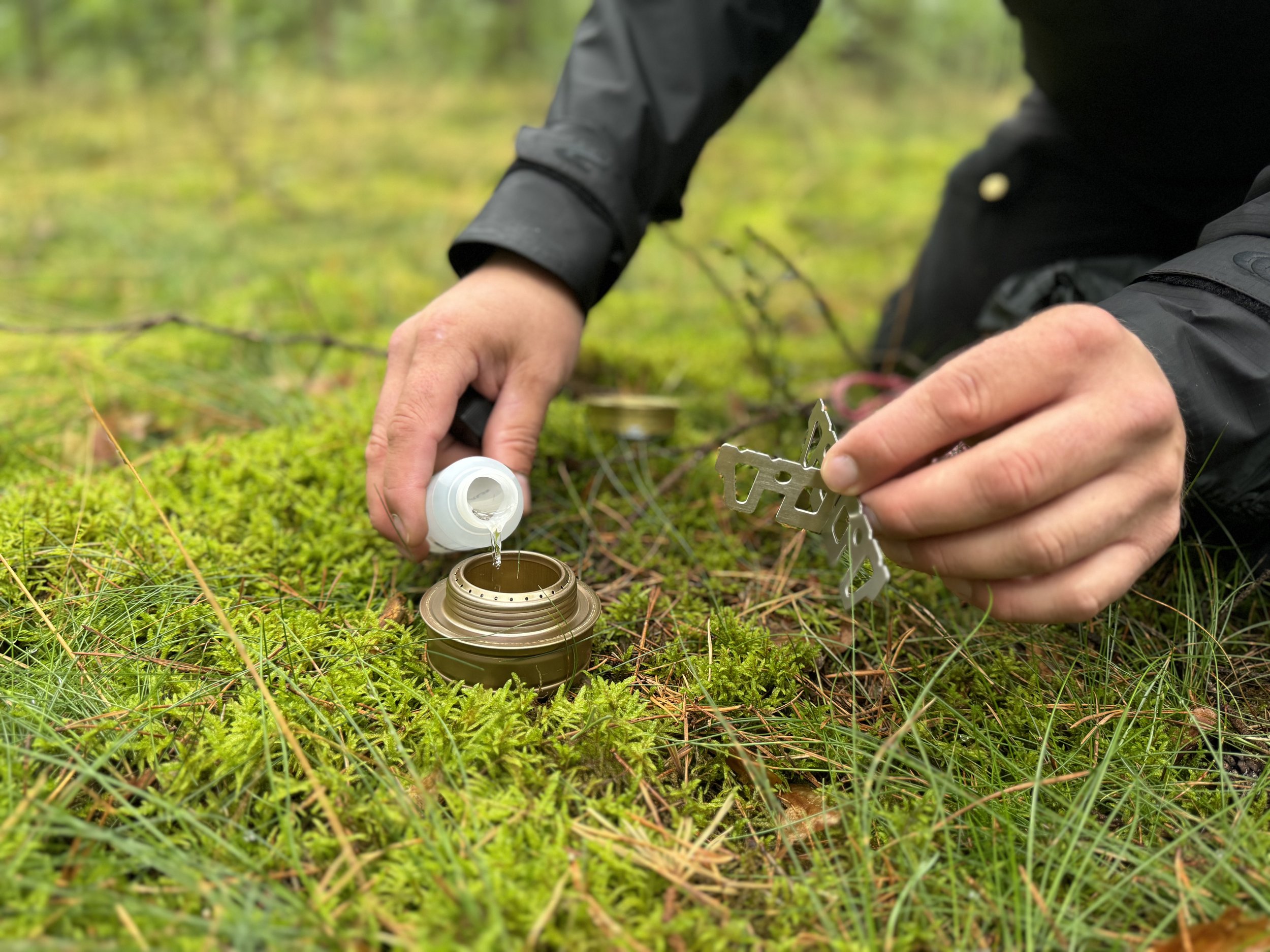 man-filling-candle-with-liquid-on-forest-floor.jpg