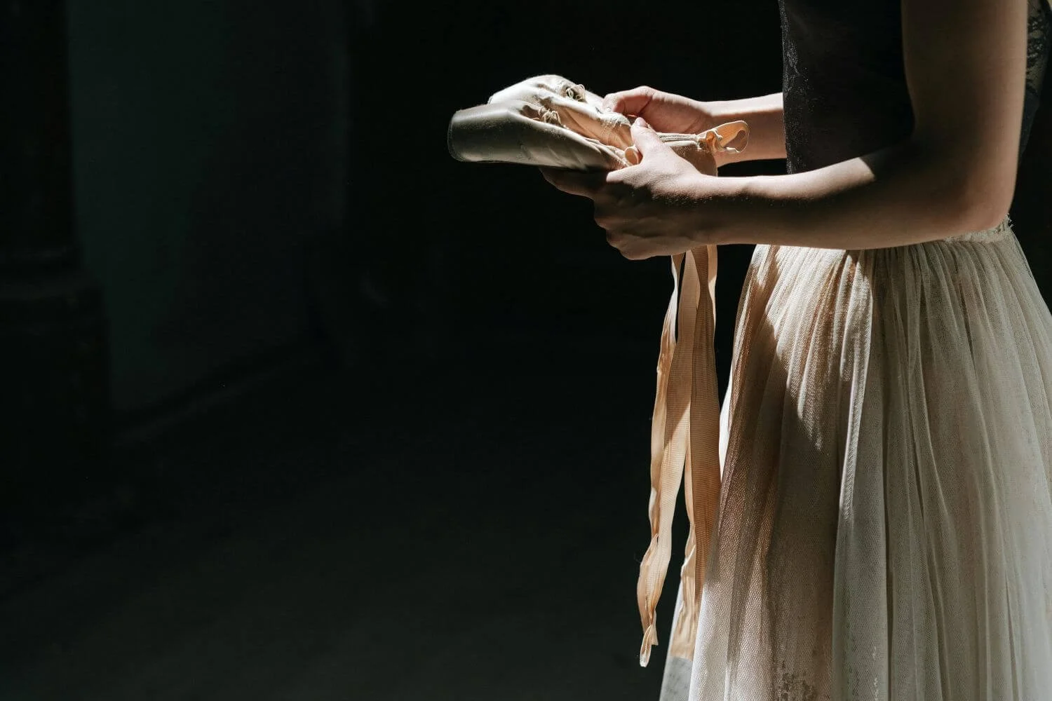 A woman holding a pair of ballet shoes in soft light, a contemplative image for trauma therapy with Rebecca Flores in San Antonio.