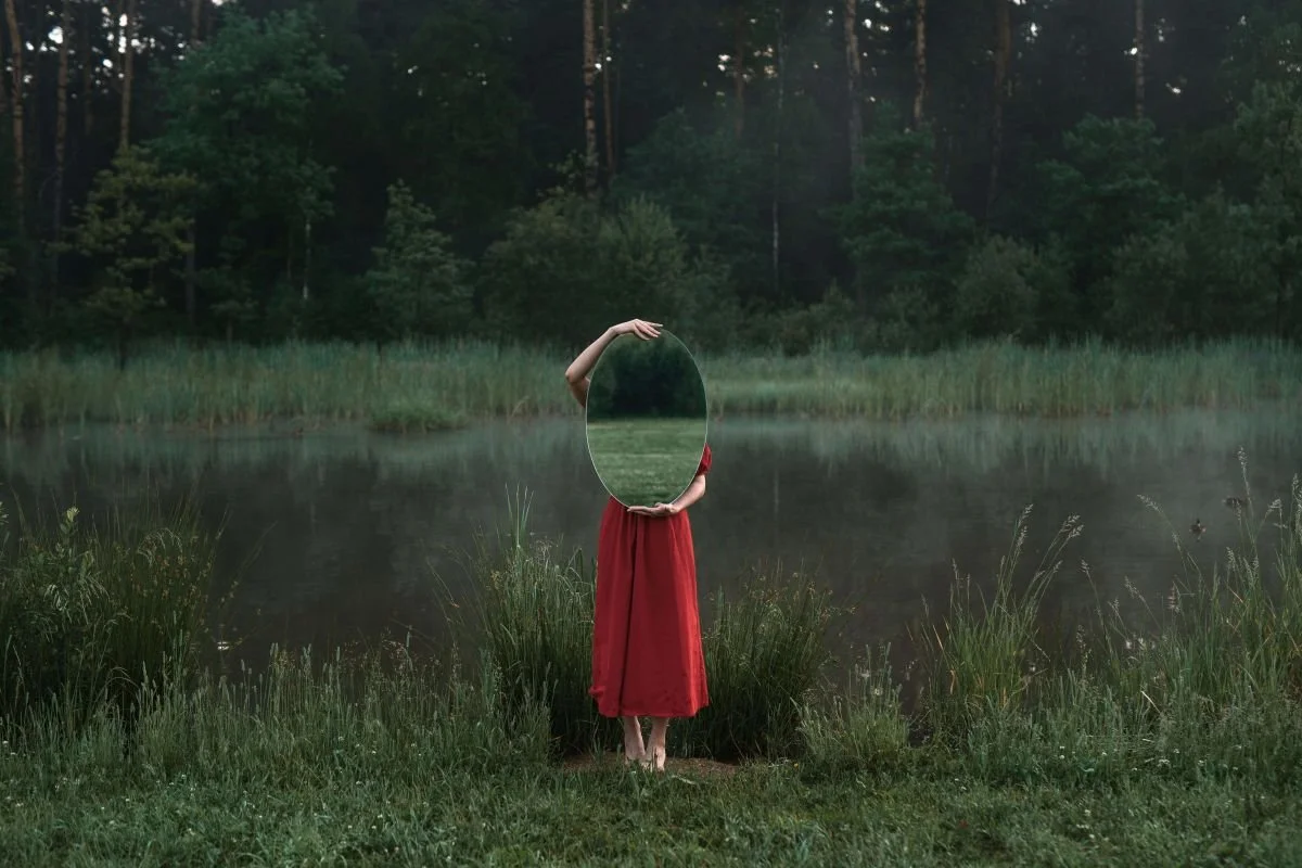 Woman in red dress standing in forest with mirror, Brainspotting therapy and self-reflection San Antonio Texas