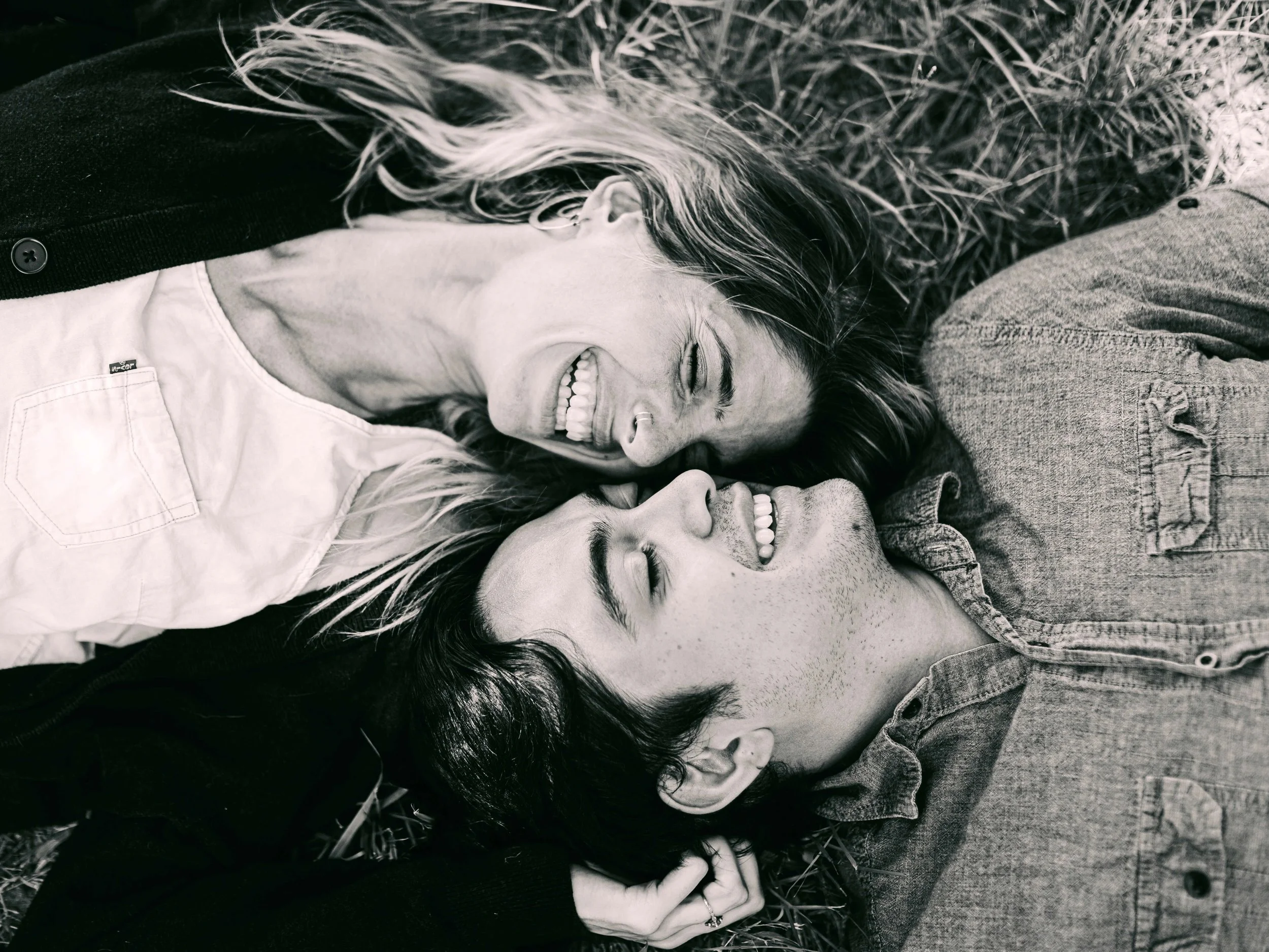 Couple laying down, smiling together in black-and-white photo, Vita Counseling Center attachment therapy for women in San Antonio, Texas
