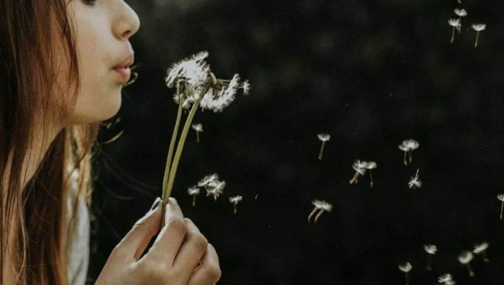 Woman blowing dandelion, grief and trauma therapy San Antonio Texas