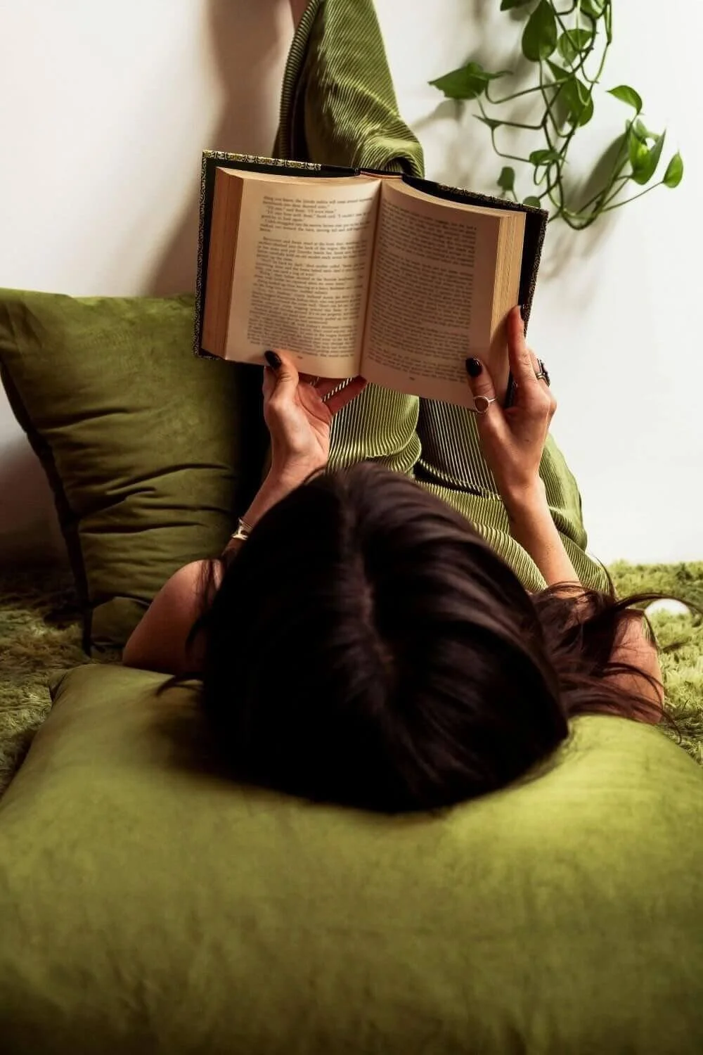 Woman reading book with legs up on wall, perfectionism therapy San Antonio Texas