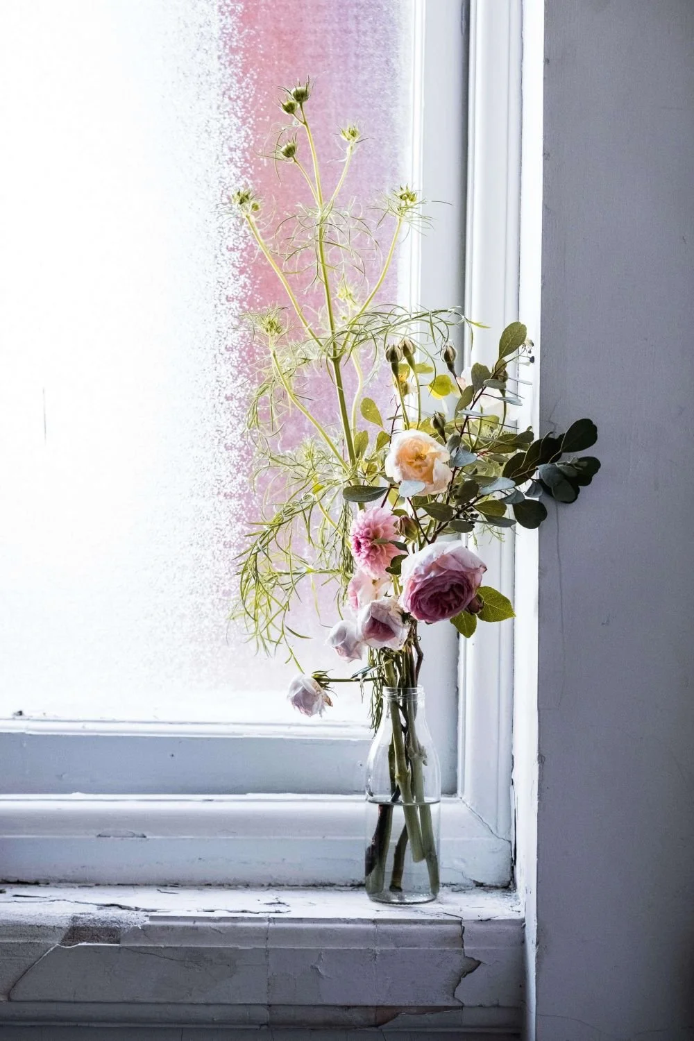 Simple floral arrangement near a sunlit window, online trauma therapy from home Texas