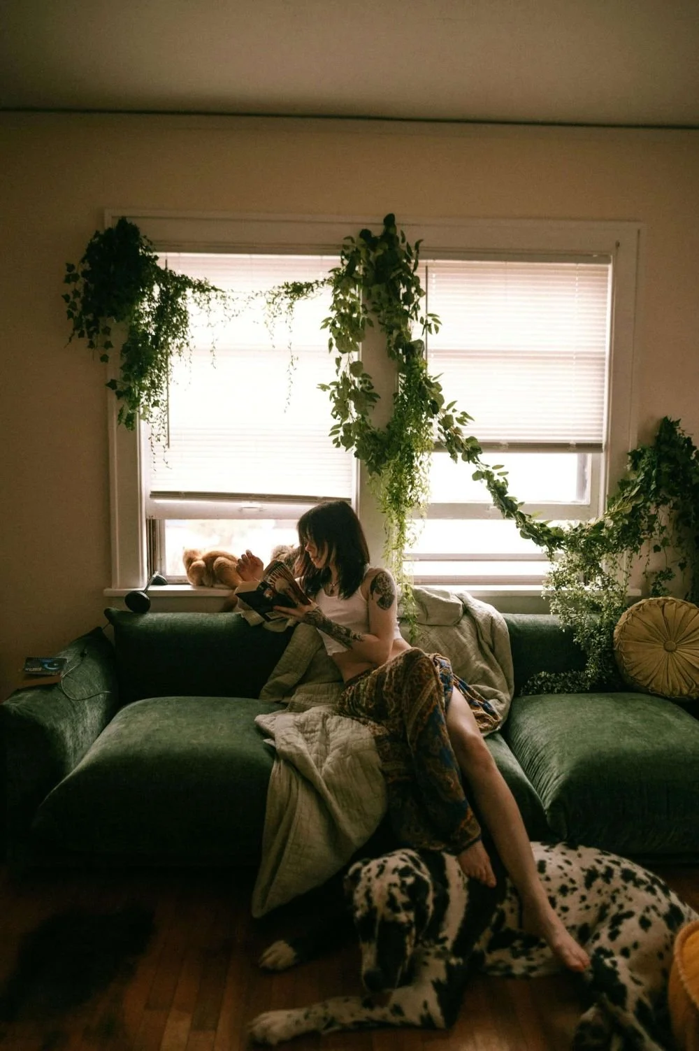 Woman reading beside large dog surrounded by indoor plants, trauma recovery therapy San Antonio Texas