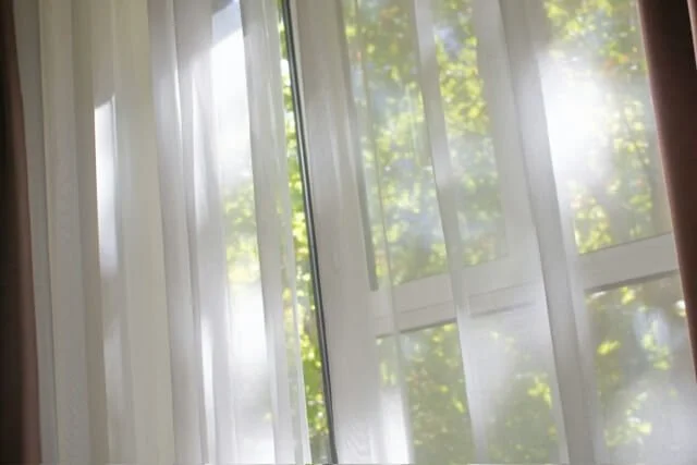 Wind blowing through sheer curtains and sunlight peeking through window, PTSD and trauma therapy in San Antonio for women with Rebecca Flores, LPC