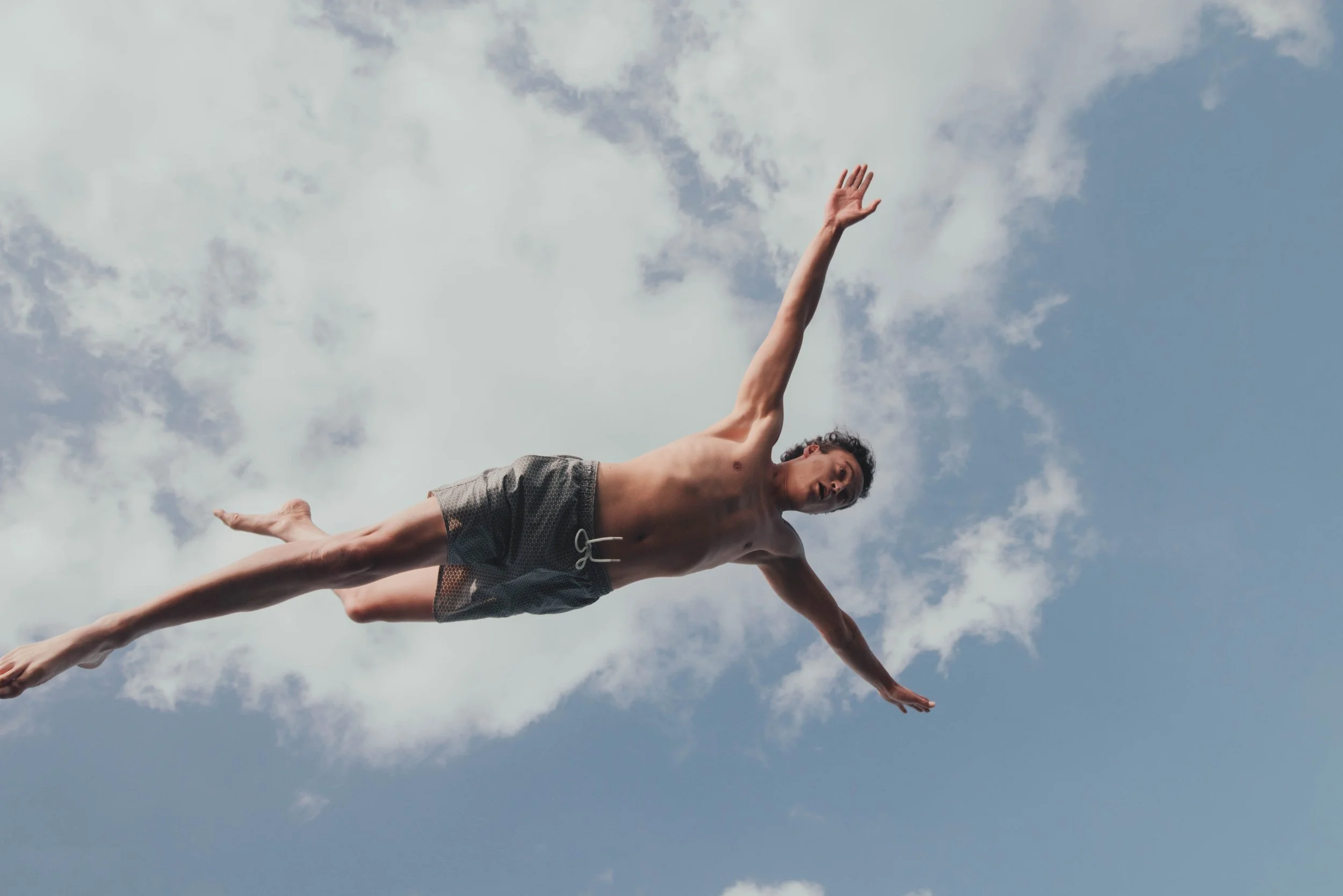 Person mid-air against a cloudy sky