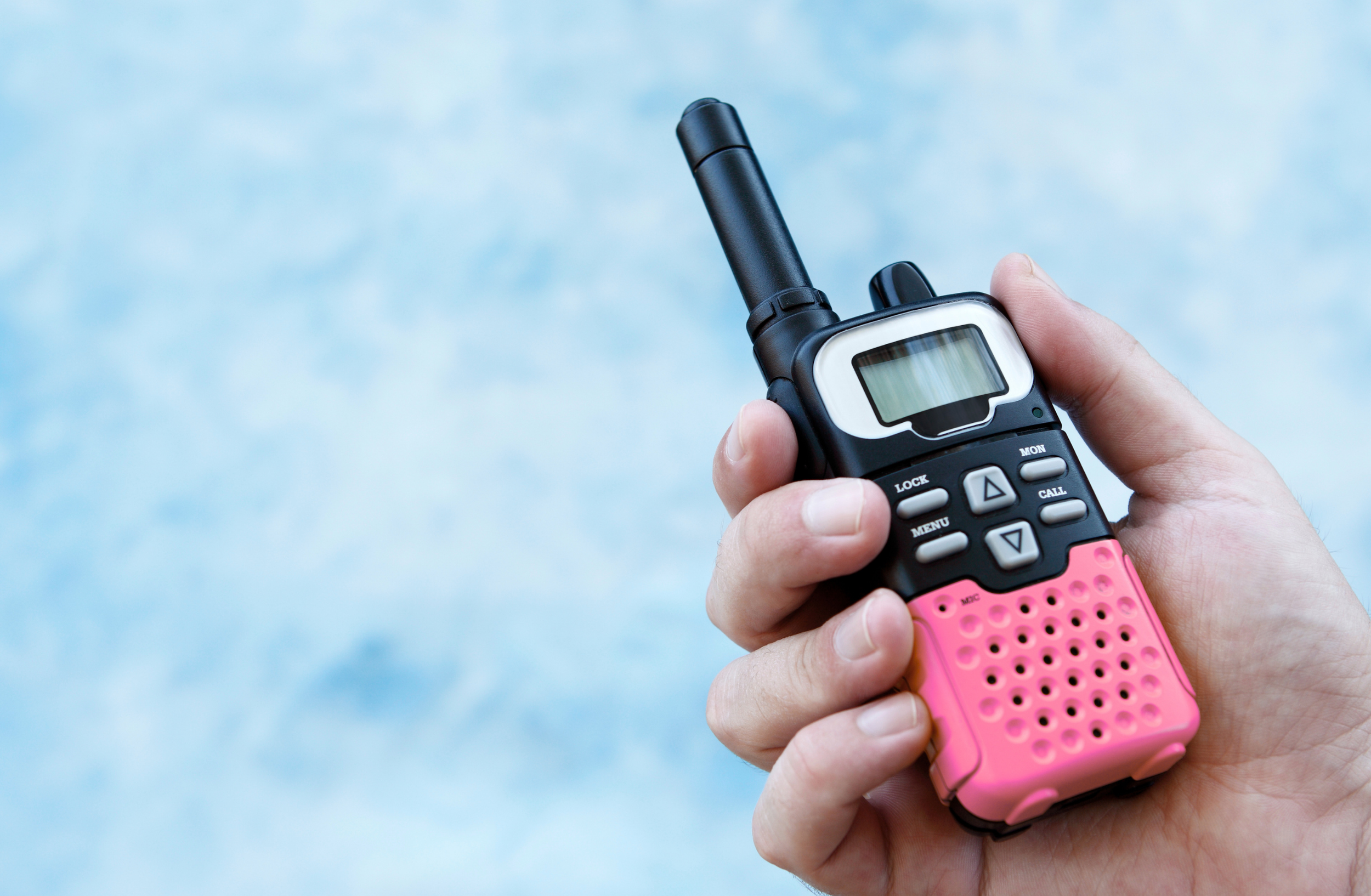 Close-up of a person holding a black and pink handheld walkie-talkie.