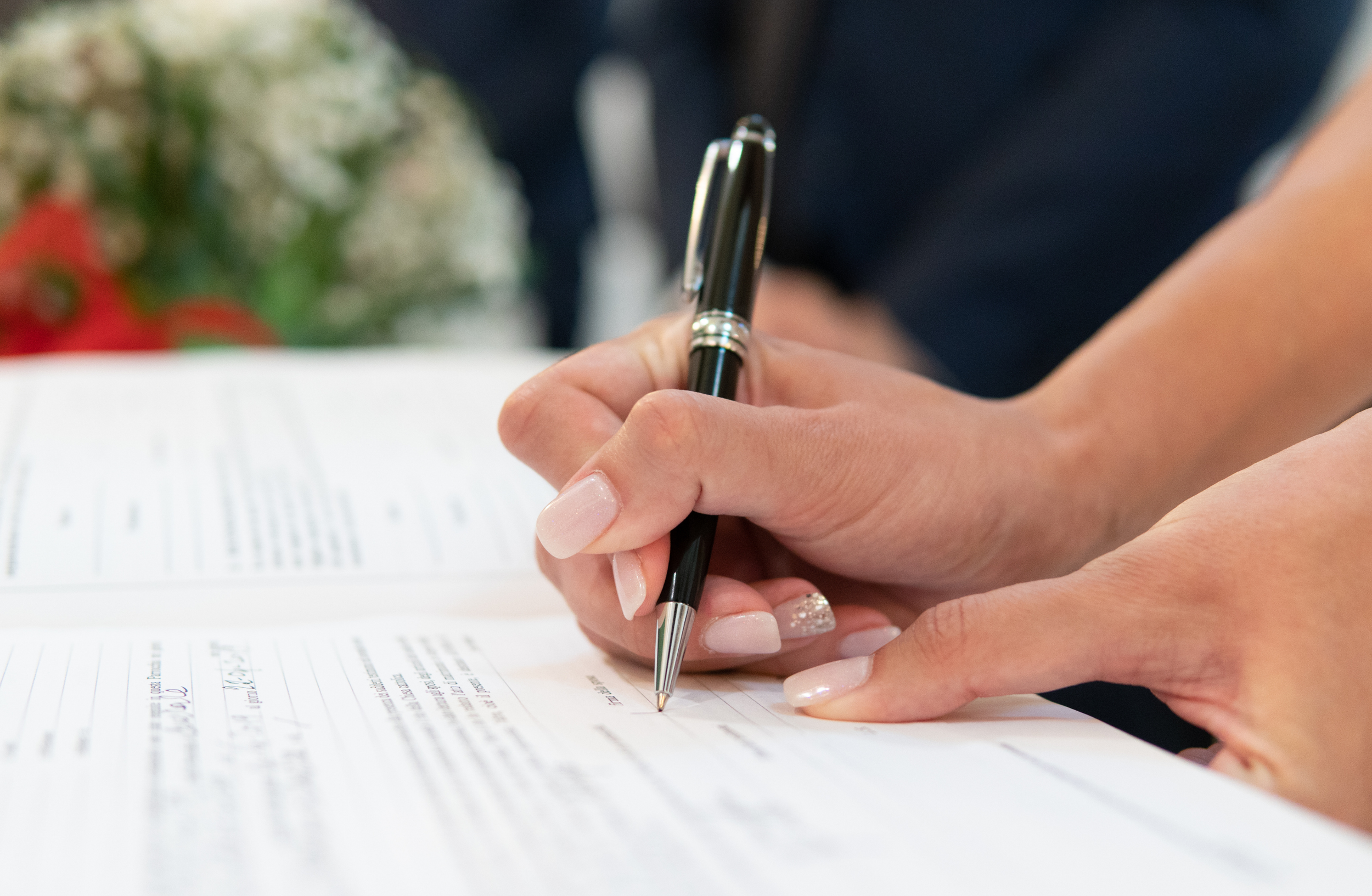Close-up of a person holding a pen and reviewing paperwork.