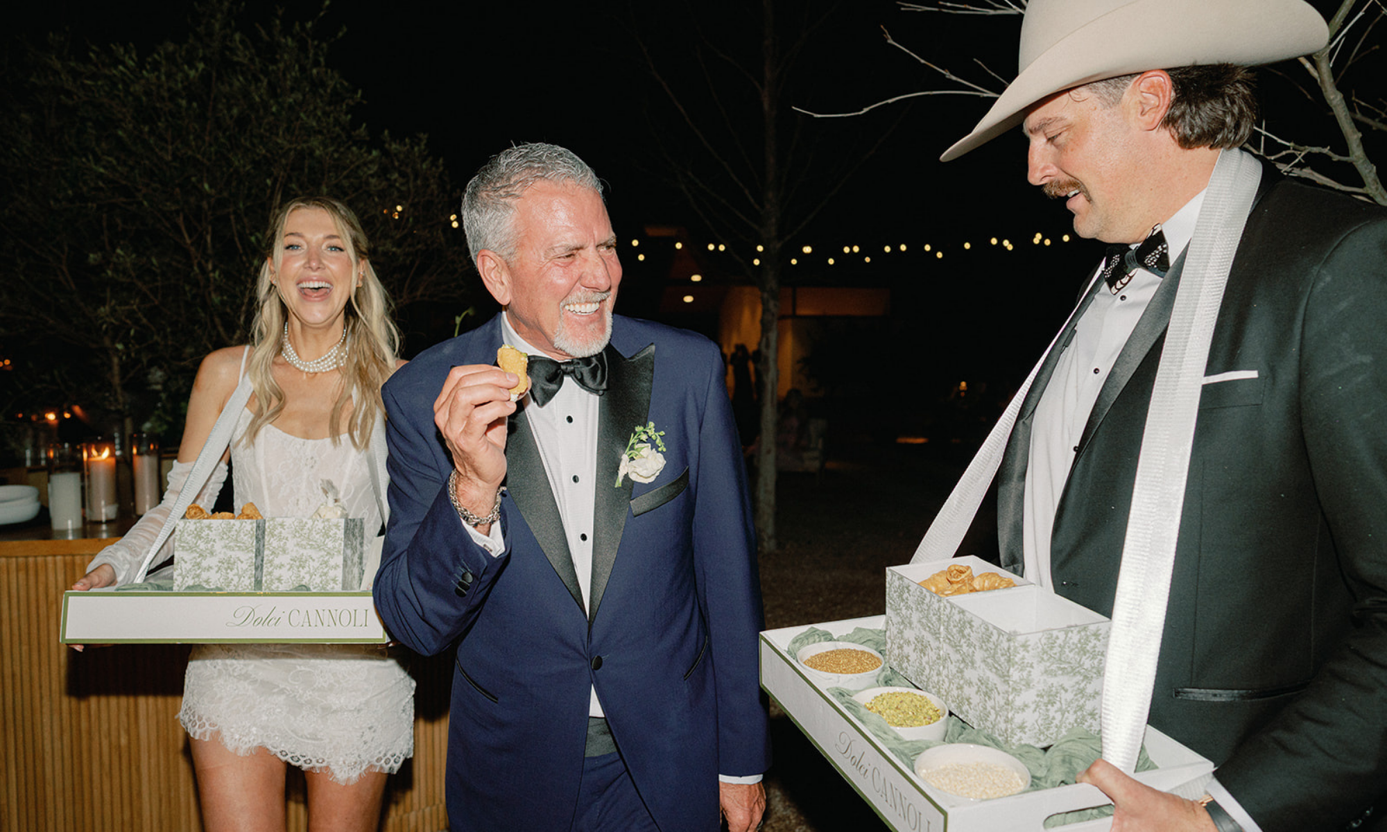 Bride and groom surprise the bride’s father with a cannoli during their wedding reception at The Grand Lady in Manor, TX, with custom Roaming Cannoli trays visible.