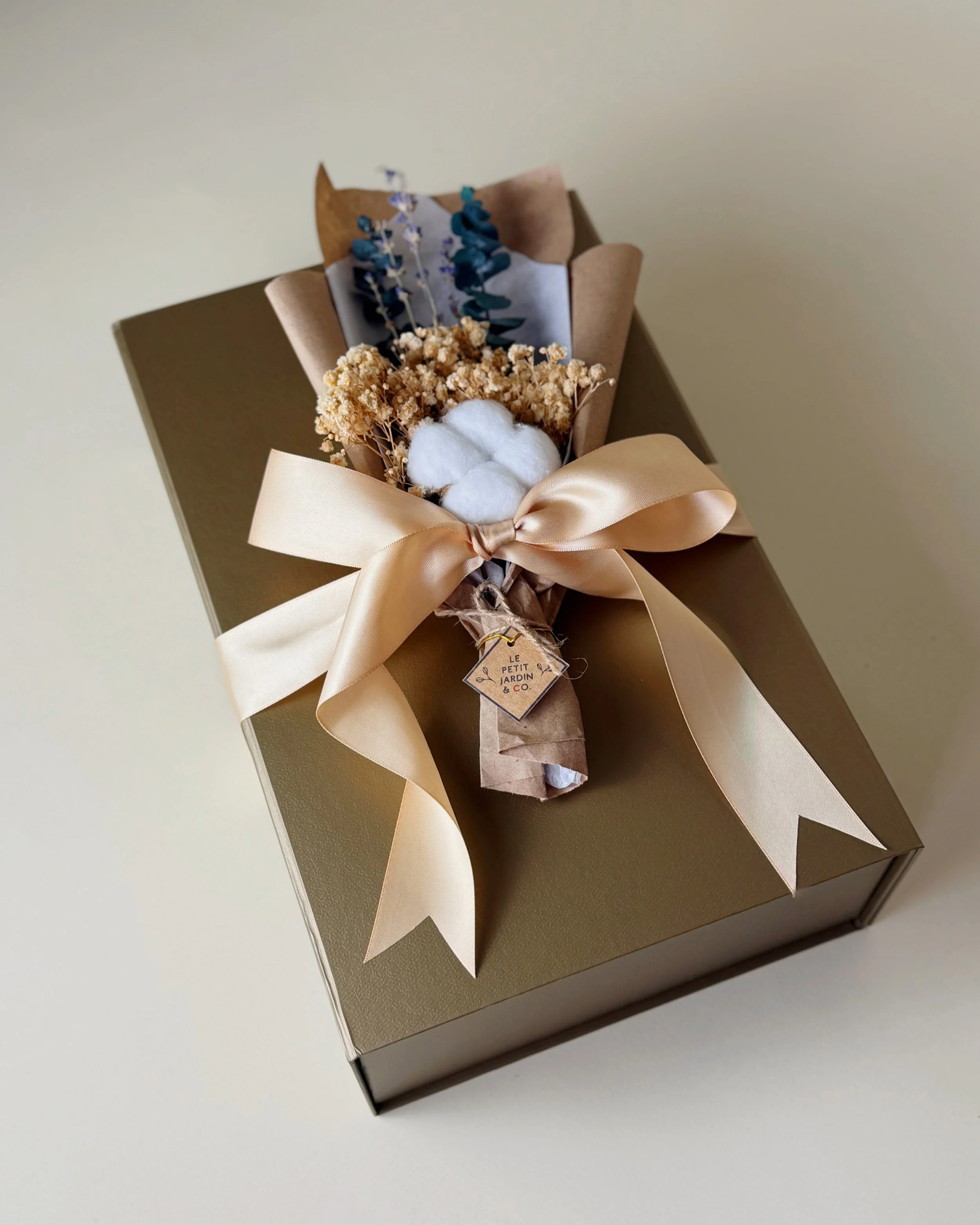 The Grand Maison Gift, featuring a cozy throw blanket, Le Jardin Reed Diffuser, Fragrance Oil, and Dried Bouquet. Gift wrapped with ribbon.