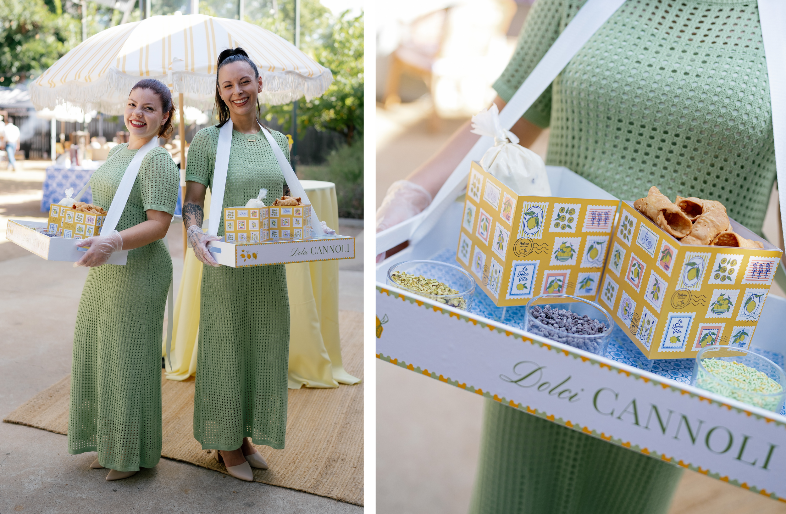 Two attendants in green dresses carry custom roaming trays filled with cannoli shells and toppings at an outdoor event.