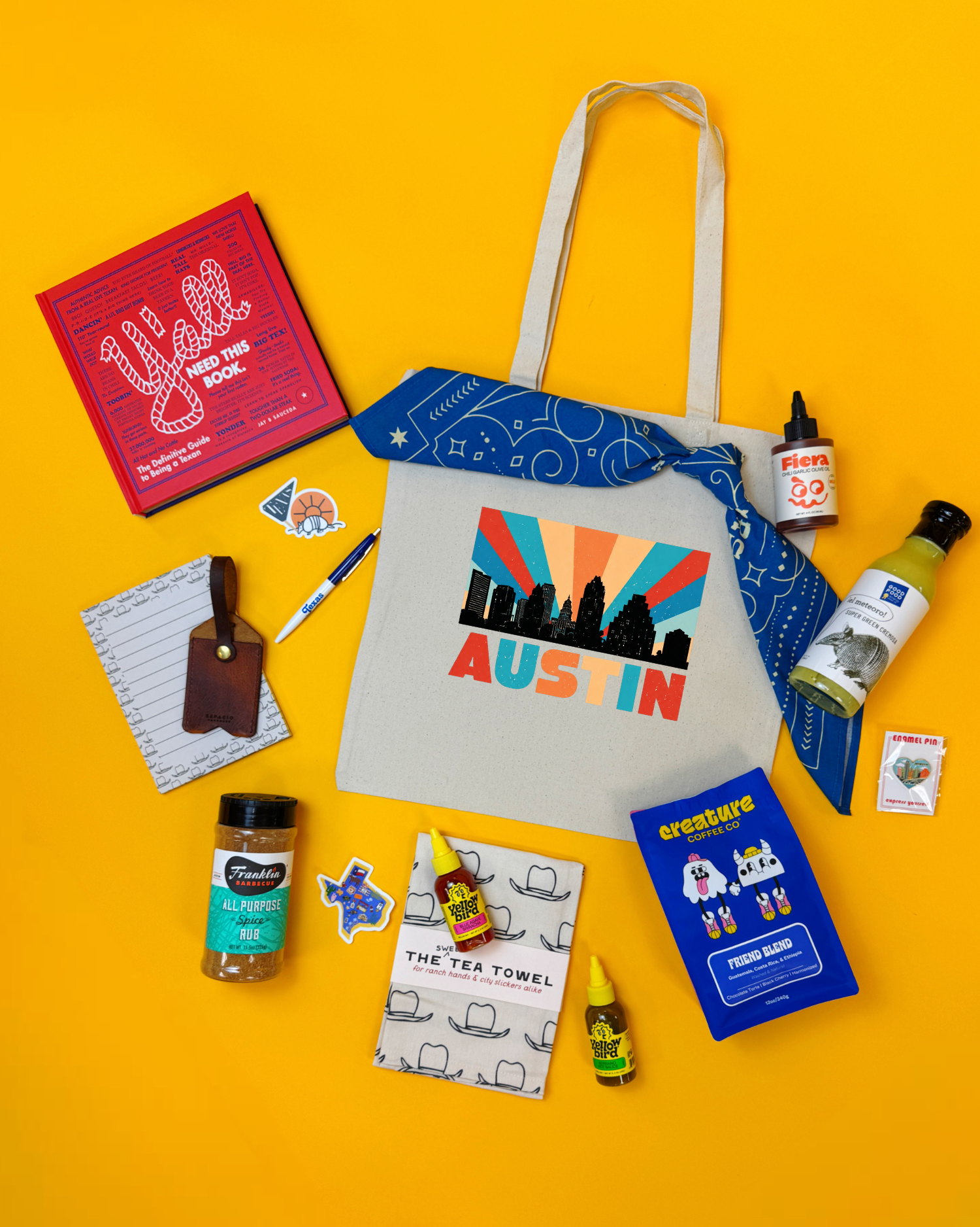 A flat lay of the Deep in The Heart gift, featuring local snacks, treats, and keepsakes from Austin companies. Packed in an Austin tote and bandana.