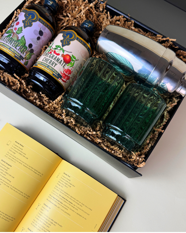 Close up of items inside Merry Cocktail Gift, including the recipe book and the green glasses